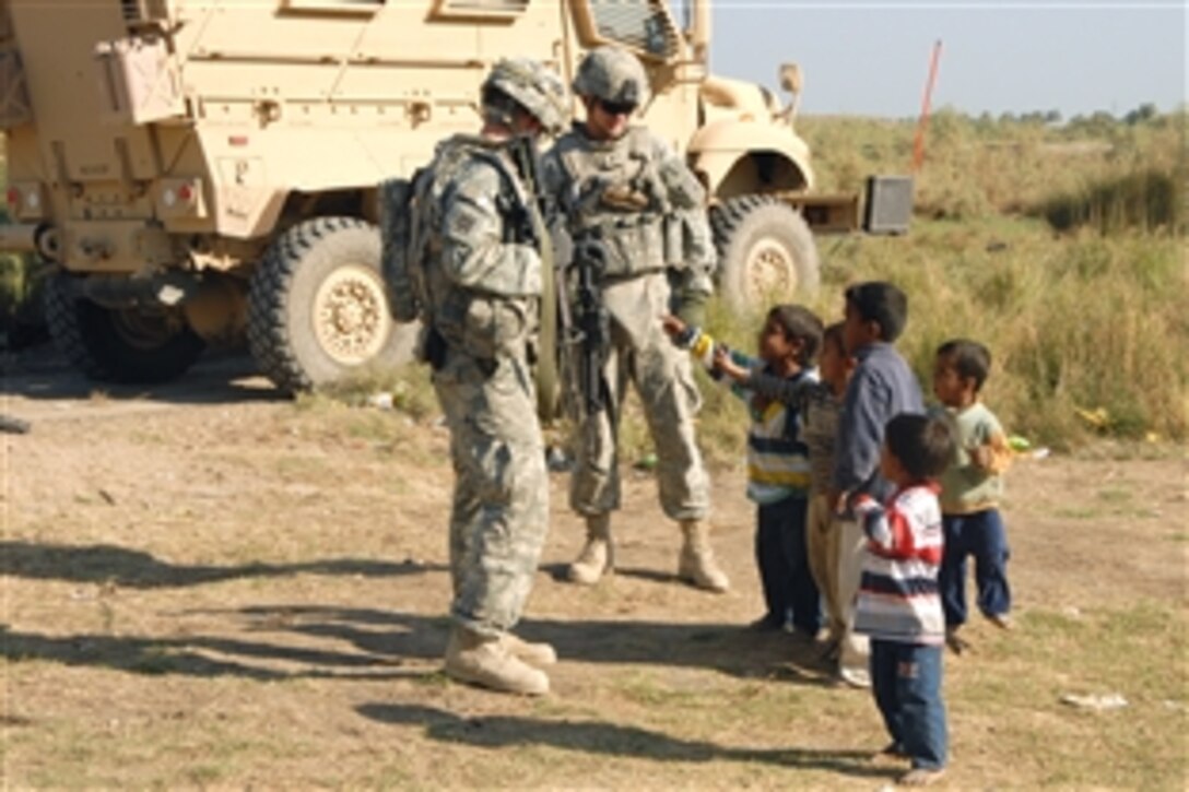 U.S. Army Sgt. Michael Taylor, left and Sgt. Matthew West talk to Iraqi children in Iskandariyah, Iraq, Nov. 7, 2008. The sergeants and fellow soldiers are assigned to Headquarters and Headquarters Company, 3rd Battalion, 7th Calvary Regiment, 4th Brigade Combat Team, 3rd Infantry Division.