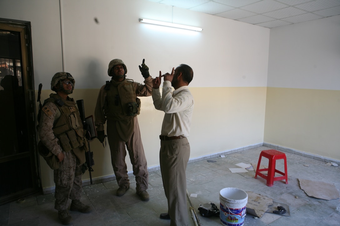 Staff Sgt. Alimare S. Ferrer, civil affairs team chief, Team 2, Civil Affairs Group, 2nd Battalion, 11th Marine Regiment, speaks with an interpreter and Iraqi contractor to discuss the plans for a new school being built in Fallujah, Iraq, Nov. 12.