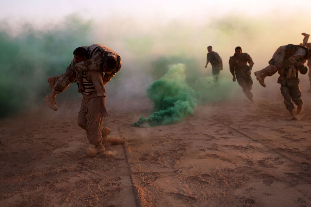 Iraqi Army and Iraqi Police teams sprint through clouds of smoke while fireman carrying simulated casualties during the Anbar Province Security Force Tactical Conditioning Competition at Combat Outpost Rawah, Iraq, Nov. 12.  The competition was coordinated by Naval Special Warfare Detachment 5 and pitted teams of Iraqi Security Forces against each other in numerous fire and maneuver and physical training exercises that helped assess skill levels and build camaraderie between the forces.::r::::n::