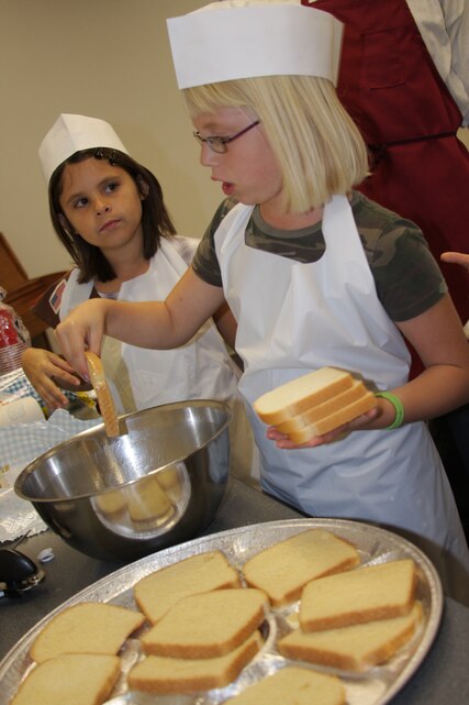 Taylor Ford and Gracie Bell Brownie Troop 618 scouts, take turns making French toast so they can earn their Make It, Eat It, Try It badges at the Protestant Chapel Nov. 13. Brownie Troop 618 earned their badges that night with the help of Chief Warrant Officer 3 Keith Mohn, the food service operations officer, and Master Sgt. Brian Velloza, a food service technician. Mohn and Velloza taught the girls how to prepare a breakfast menu, which included French toast, bacon, sausage, hash browns, fruit salad, and fruit punch to drink.