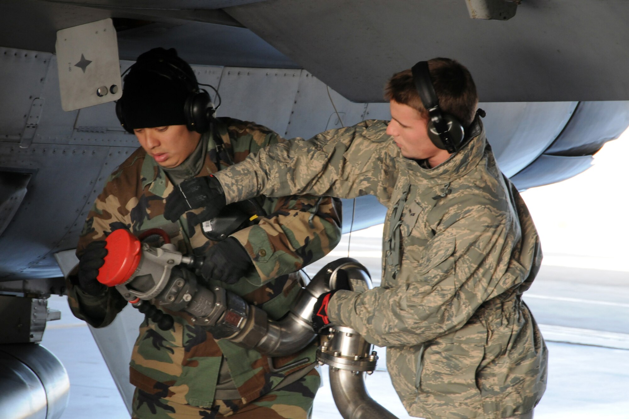 MISAWA AIR BASE, Japan -- Senior Airman Johnathan Bren, 35th Aircraft Maintenance Squadron, and Airman 1st Class Casey Kubik, 35th Logistics Readiness Squadron, secure a single point nozzle during the hot-pit refueling of an F-16, Nov. 10, 2008. Hot refueling, also known as a hot pit, is a procedure that allows the aircraft to refuel while the engines are still on, thus cutting the time needed to refuel by more than half. (U.S. Air Force photo by Airman 1st Class Jamal D. Sutter)