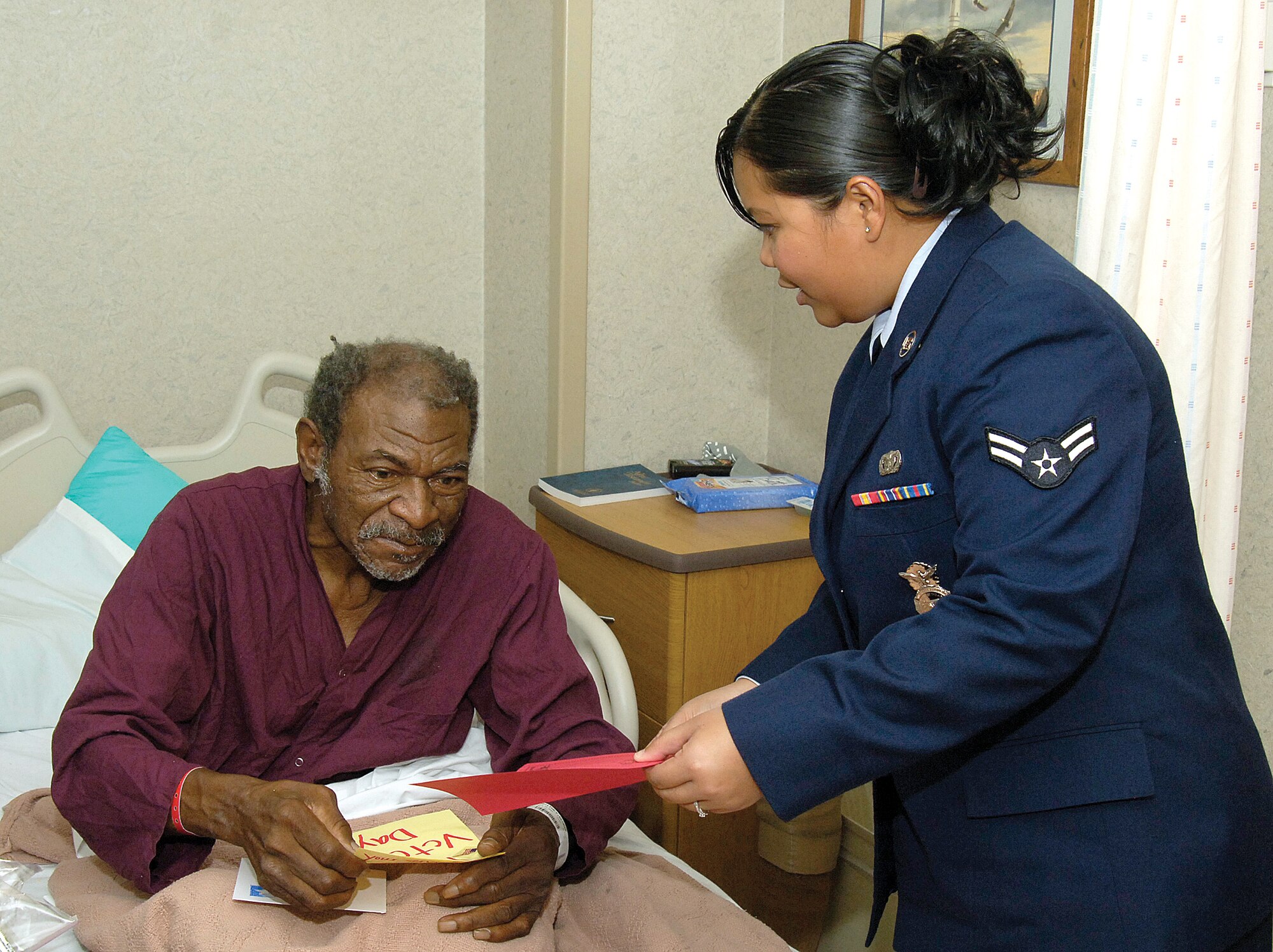 Airman 1st Class Edrianne Flores-Tullis, 72nd Security Forces Squadron, greets Army veteran George Whitney with schoolchildren-made Veterans Day cards during a visit to the Oklahoma City Veterans Affairs Medical Center Nov. 10. Airman 1st Class Edrianne Flores-Tullis, 72nd Security Forces Squadron, greets Army veteran George Whitney with schoolchildren-made Veterans Day cards during a visit to the Oklahoma City Veterans Affairs Medical Center Nov. 10.  (Air Force photo/Margo Wright)
