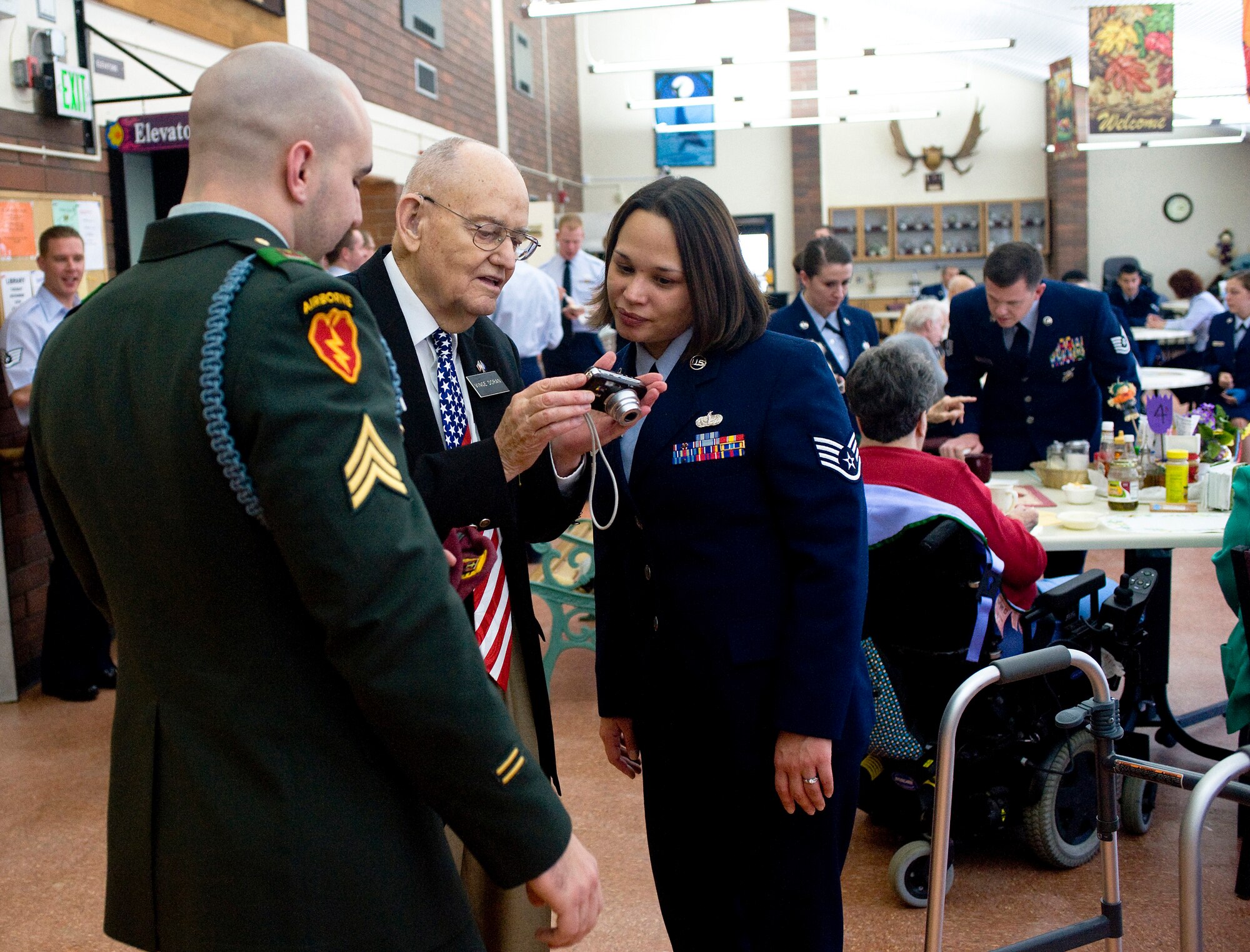 ANCHORAGE, Alaska -- Army Sgt. Michael Albright and Staff Sgt. Mary Albright look at a photo with Vince Doran, a World War II veteran, at Anchorage Pioneer Home Nov. 7. Arctic Warriors spent some time with veterans to socialize and eat ice cream. (U.S. Air Force photo/Senior Airman Jonathan Steffen)