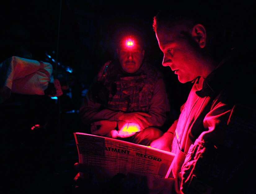 Capt. James Ryan checks patient records with light from Master Sgt. Scott Wilkes' head lamp during an aeromedical evacuation mission over Iraq Nov. 7. Two Iraqi doctors from Iraq's Ministry of Defense accompanied the Air Force mission to study aeromedical evacuation procedures so that they can establish an aeromedical evacuation service for the Iraqi air force. Captain Ryan, a flight nurse with the 332nd Expeditionary Aeromedical Evacuation Flight, is deployed from McChord Air Force Base, Wash. Sergeant Wilkes, a medical technician with the 332nd EAEF, is deployed from McGuire AFB, N.J. (U.S. Air Force photo/Airman 1st Class Jason Epley)