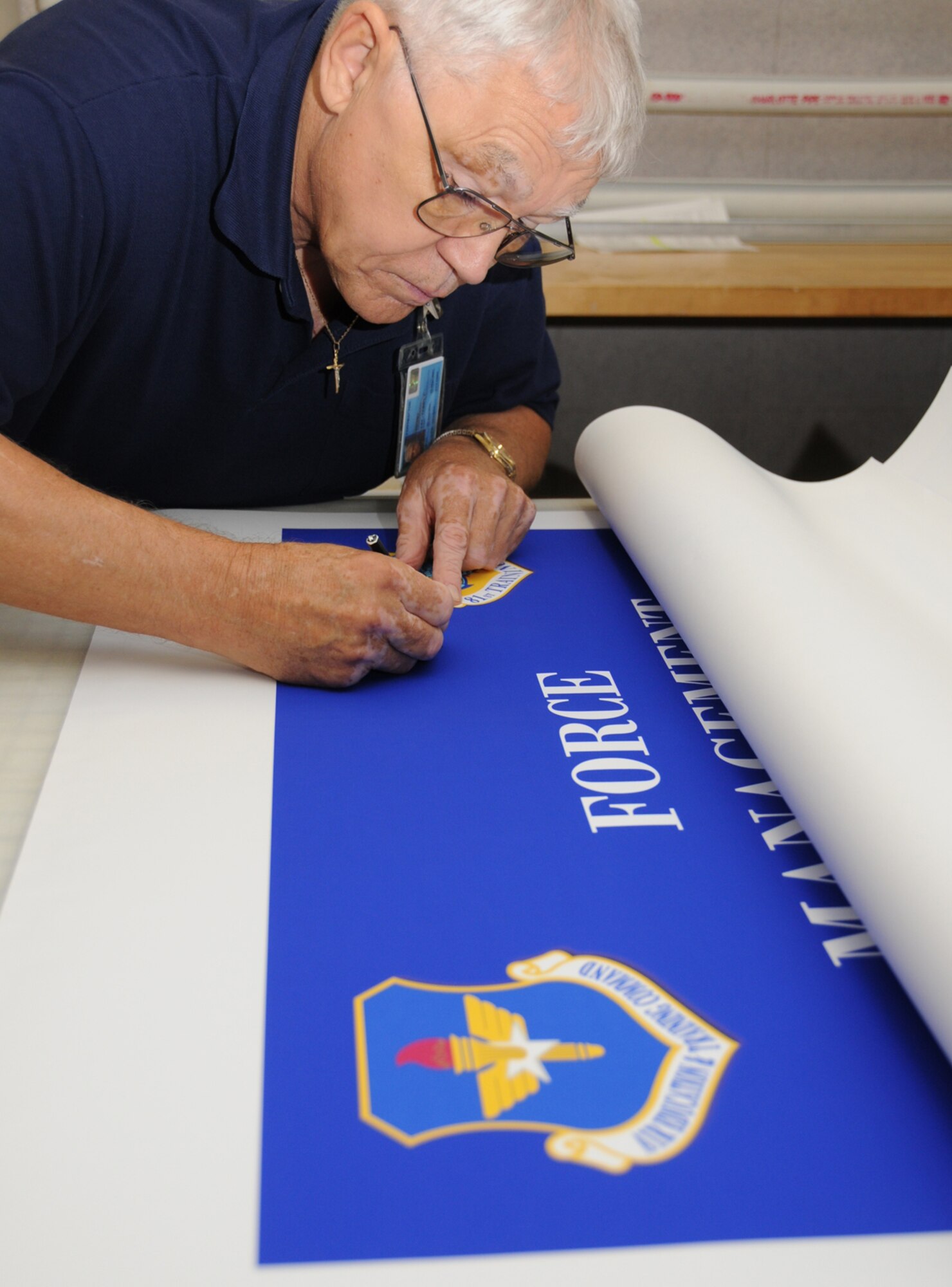 Graphics illustrator Terry Lee prepares a poster for lamination.  (U.S. Air Force photo by Kemberly Groue)