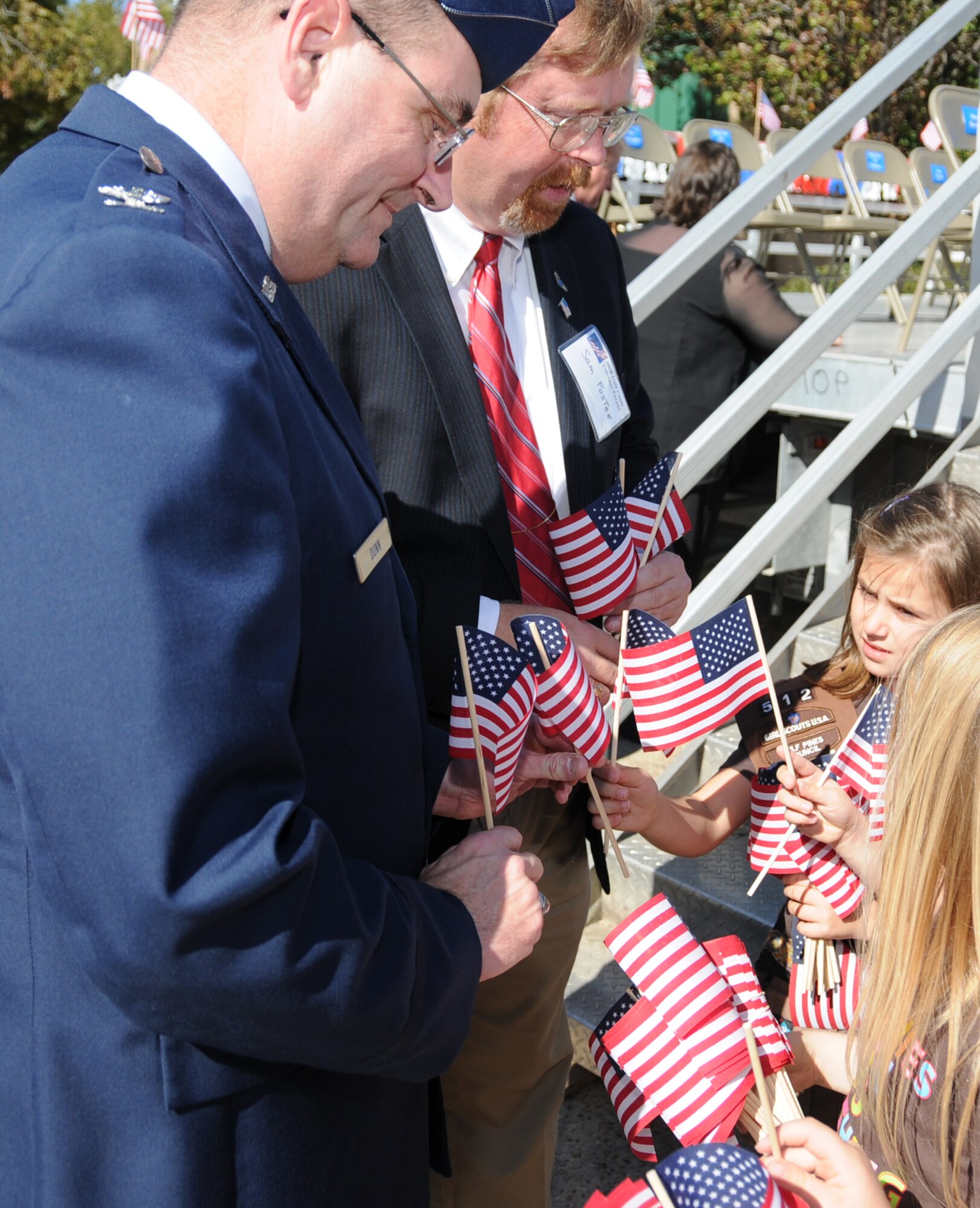 Chaplain (Col.) Rich-ard Dunn, left, and Sam Foster, director of staff for the 81st Training Wing, get American flags from Carson Miller, 7, from Brownie Troop 512 of Gulfport before the start of Saturday’s Gulf Coast Veterans Day Parade in Biloxi.  Carson’s parents are Jamie and Kelli Miller.  (U.S. Air Force photo by Kemberly Groue)