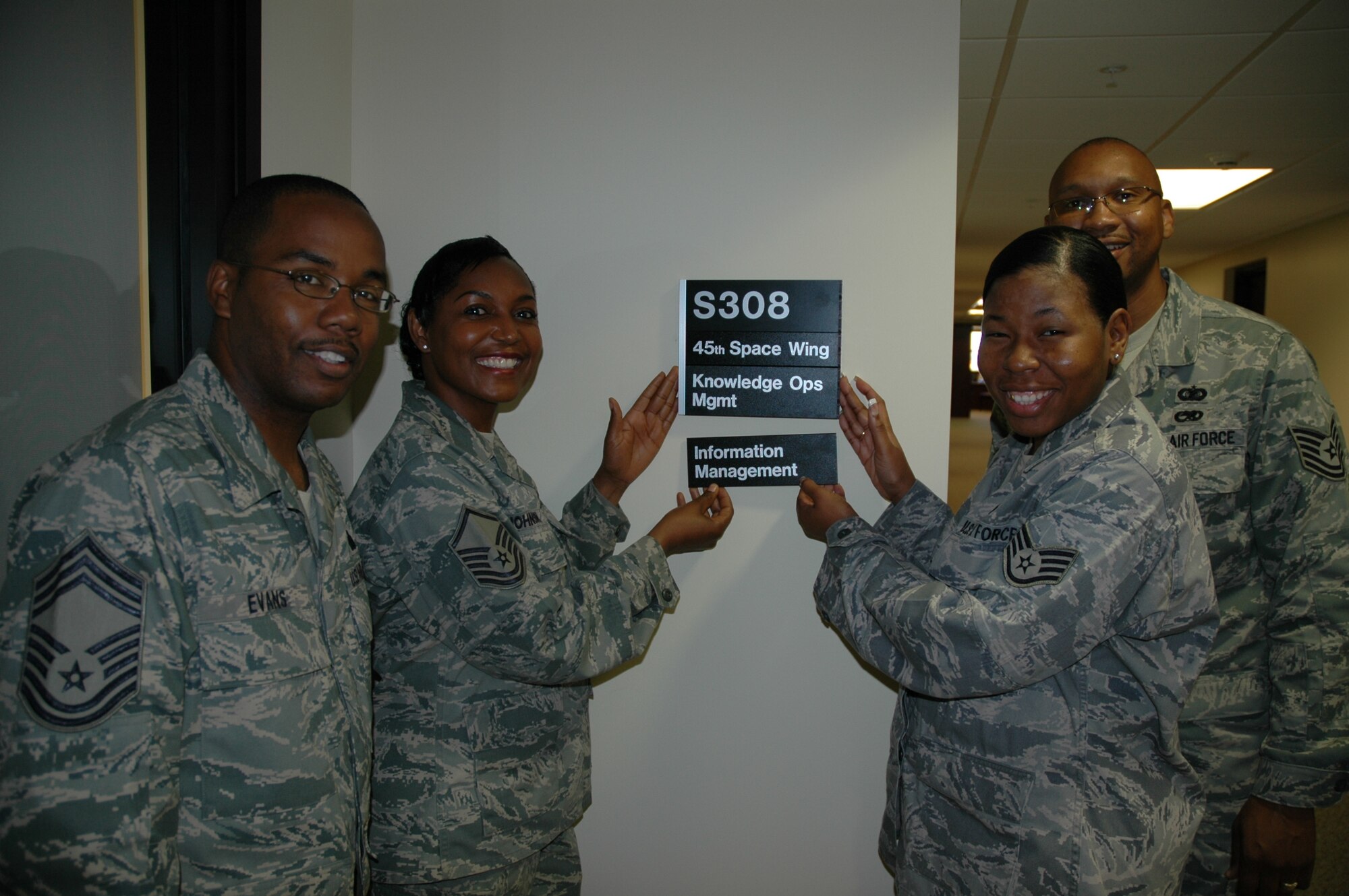 Chief Master Sgt. Frank Evans, Master Sgt. Christine Johnson, Staff Sgt. Ericka Wright and Tech. Sgt. Rodney Huffman proudly put up their new office nameplate as their office name officially changes from Information Management to Knowledge Operations Management. The change is part of the AF Roadmap for Development of Cyberspace Professionals to mitigate the effects of a manpower authorization reduction yet ensure effective and efficient IM services to the warfighter. (U.S. Air Force photo by Airman 1st Class David Dobrydney)