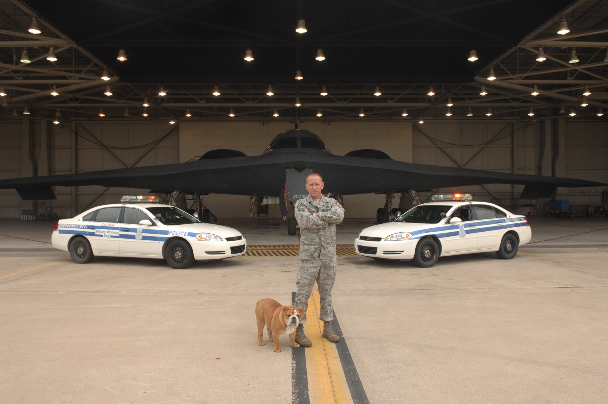 WHITEMAN AIR FORCE BASE, Mo. – Chief Master Sgt. Brian Hornback, 509th Bomb Wing command chief master sergeant, stands in front of two security forces vehicles and a B-2 with his dog, Red, for a photo Nov. 13. The photo will be used to make posters for Airmen Against Drunk Driving and will include the text “The only thing me and my dog Red hate more than cats is drunk drivers.”  AADD can be reached at 563-1178. (U.S. Air Force photo/Senior Airman Jessica Snow)