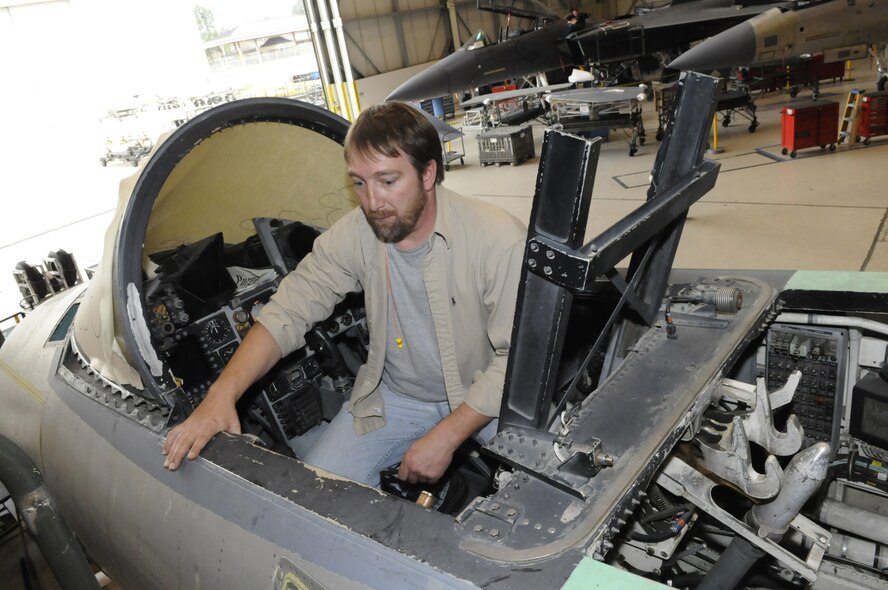 Darren McLeod, who is part of the longeron team, shows where the longerons are located on the aircraft from the cockpit of an F-15. U. S. Air Force photo by Sue Sapp