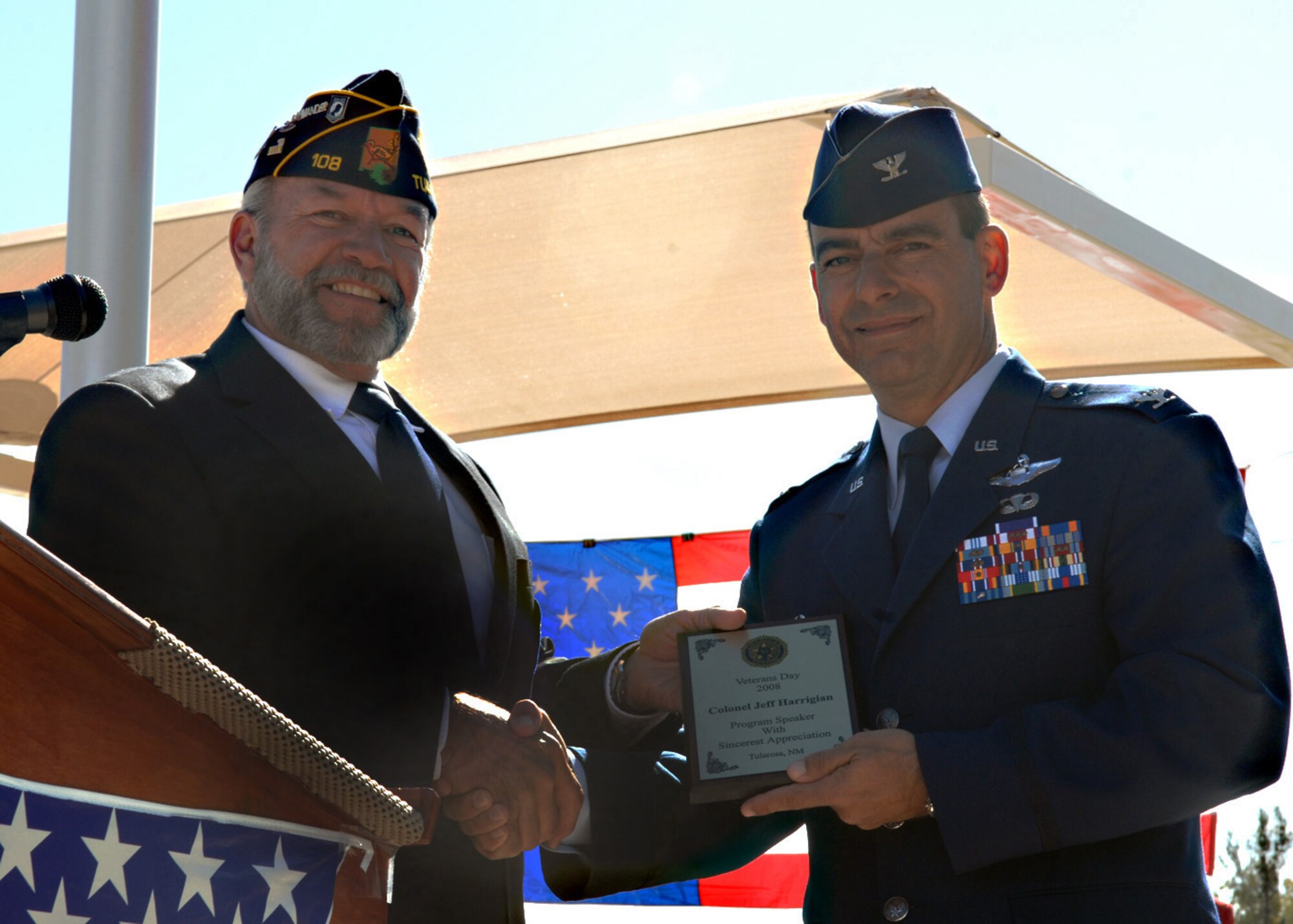 Ed Summerall, American Legion Post 108 commander, presents Col. Jeff Harrigian, 49th Fighter Wing commander at Holloman Air Force Base, N.M., with a plaque of  appreciation during the Veterans Day Observance ceremony, Nov. 11. As a guest speaker, Colonel Harrigian showed his appreciation with a speech for all veterans that gathered together at the Tularosa Veterans Memorial Park, N.M. (U.S. Air Force photo/Airman 1st Class Veronica Salgado)