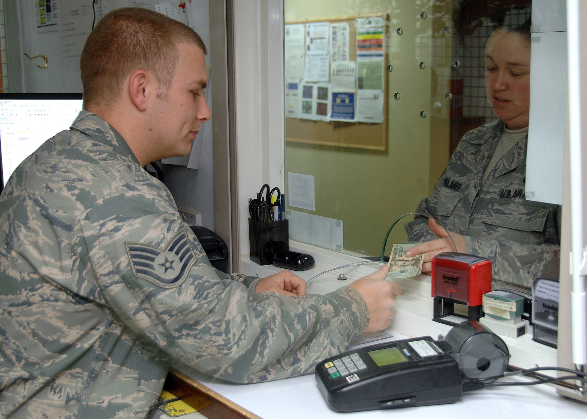 SOUTHWEST ASIA -- Staff Sgt. Ronald Brewer, 386th Air Expeditionary Wing Finance office, hands money to Tech. Sgt. Michelle Palmer, 386th Air Expeditionary Wing, after she makes a withdrawal from her Eagle Cash card on Nov. 10 at an air base in Southwest Asia. Eagle Cash is a management tool designed to support U.S. military personnel deployed in combat zones and peacekeeping missions. The Finance office has issued more than 3,500 Eagle Cash cards since January 2008. Sergeant Brewer is deployed from the Tennessee Air National Guard. Sergeant Palmer is deployed from Dover Air Force Base, Del. (U.S. Air Force photo/Tech. Sgt. Raheem Moore)
