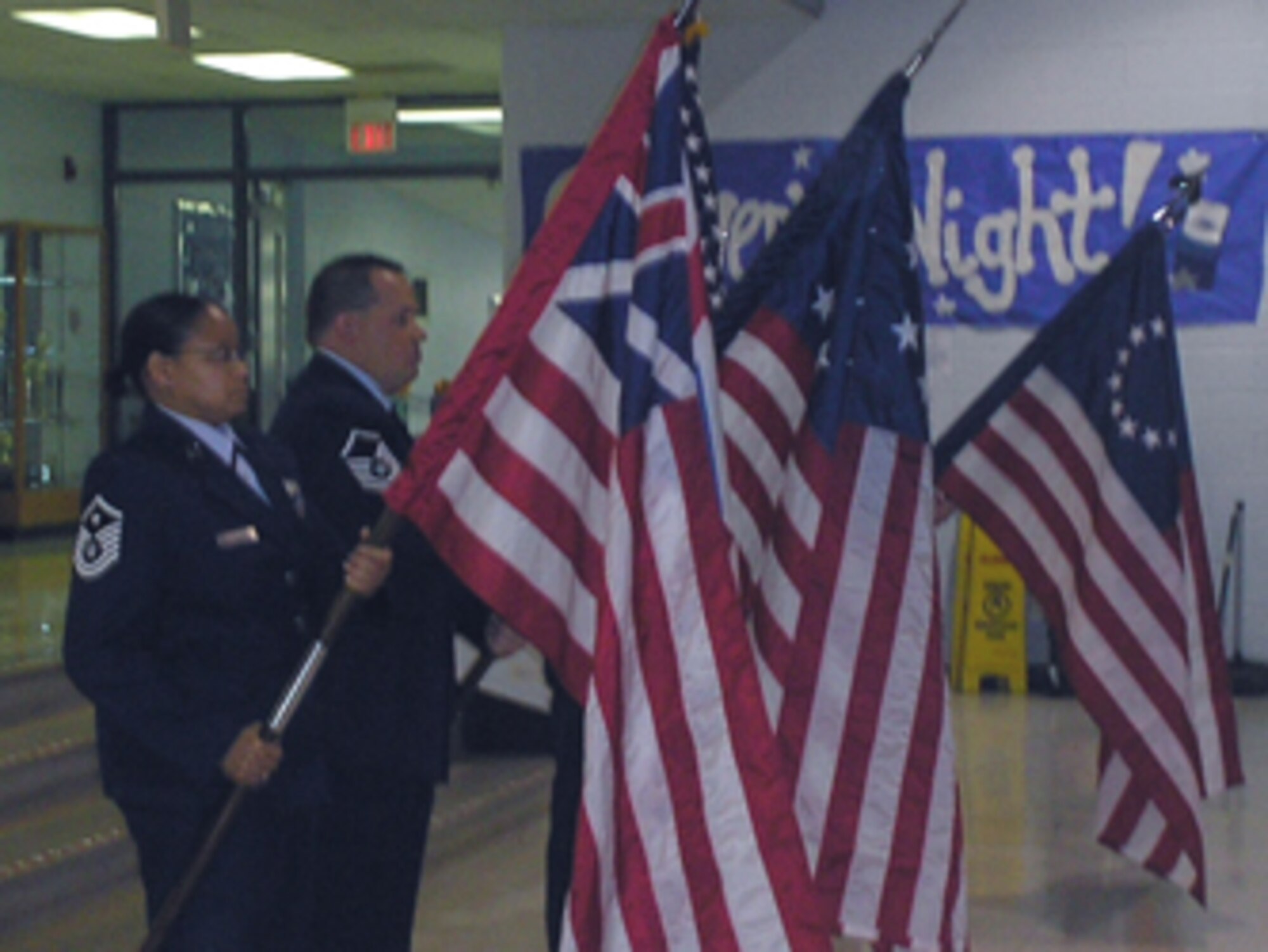 Master Sgt. Crystal Johnson, 131st Logistics Readiness Squadron 1st Sgt., and Master Sgt. Richard Champ, 131st Fighter Wing financial management superintendent and NCOAGA Chapter 14 President, hold their flags at an angle to salute the Flag of the United States of America during the Pledge of Alligiance at Dardenne Elementary School Nov. 11.  Sergeants Johnson and Champ participated in Operation Patriotism in honor of Veteran's Day. (Courtesy Photo)