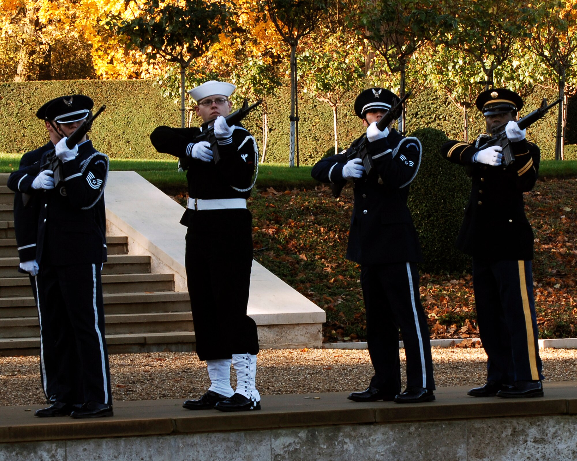 CAMBRIDGE AMERICAN CEMETERY, United Kingdom -- A combined rifle team from the RAF Alconbury Honor Guard and the JIOCEUR Honor Guard fires a volley during the Veterans Day Commemoration Nov 12,2008. The members of the rifle team are (L-R) Air Force Technical Sgt. Dawn Dean, Petty Officer 3rd Class  William J. Noble, Senior Airman Joshua Tuccolo, and Army Sergeant Rodney T. Risher. Members of the United States Air Force , Army, Marines and Navy,  along with the Royal Air Force, Air Force Junior ROTC, fire and police services, American and British veterans and families of fallen service members gathered here today to honor America’s Fallen. Cambridge American Cemetery is the final resting place of 3,812 American servicemen and women who gave their lives to the cause of freedom. The the Veterans Day Commemoration is an annual event planned and organized by the 501st Combat Support Wing headquartered at RAF Alconbury United Kingdom.(U.S. Air Force photo by Staff Sgt. Chad E. Chisholm)  