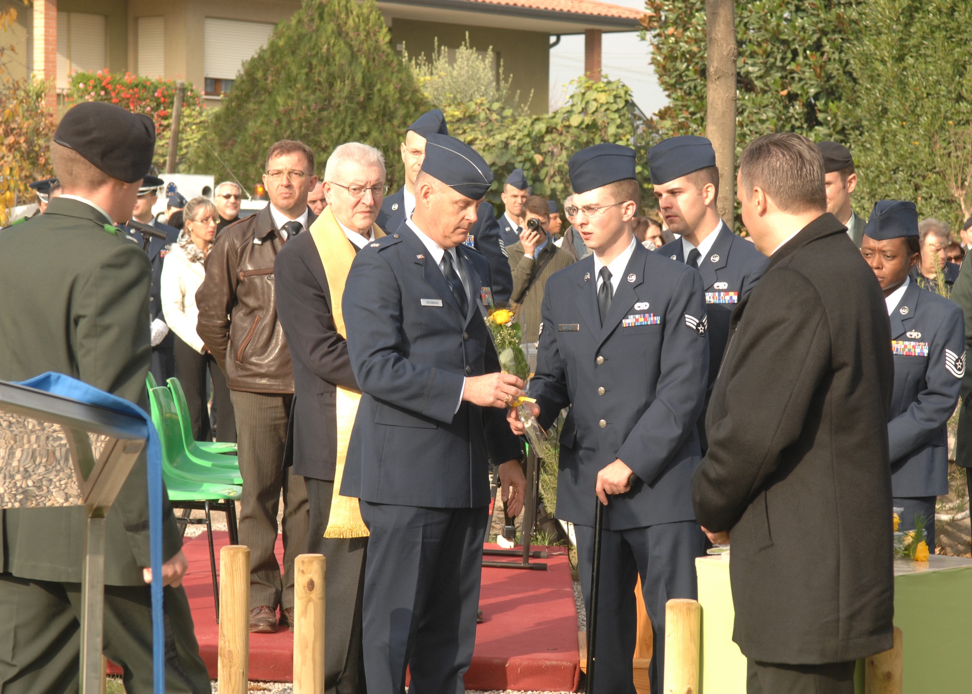 Lt. Col. Jim Browning, 31st Fighter Wing chaplain, hands Senior Airman Michael Costly a single yellow rose to place on the UH-60 Helicopter Crash memorial  in Santa Lucia di Piave, Italy, on Nov. 8 in honor of those military members who lost their lives in the crash one year ago. Airman Costly was one of five survivors of the crash. (U.S. Air Force photo/Senior Airman Taylor Marr)