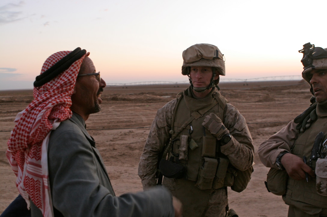 Lt. Col. Andrew J. Drake, plans officer, jump command point, Multi National Force - West, and 'Moose,' a linguist, speak with Ali Awad, a farmer in the countryside outside Al-Ba'aj.  The visits Drake conducts on an almost daily basis are meant to build a rapport with his neighbors to increase security in the area and obtain information.