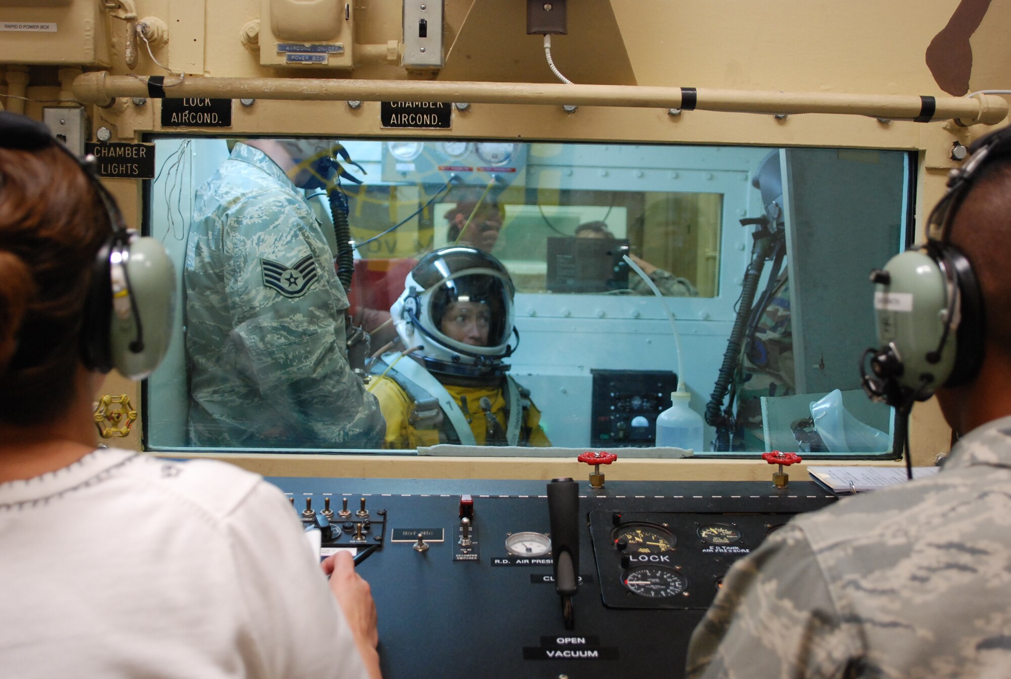 Claire Rowan, an Aerospace Physiological Training Flight assistant technician director,and Airman Jimmy Sayarath, an APTF Aerospace Physiological Technician monitor the high-altitude chamber flight Nov. 13, while Lane Wallace is assisted inside the chamber by Staff Sgt. Joe Mesa and Staff Sgt. Jennifer Gilroy. The chamber flight is where all members of the APTF come together and work as one. (Photo by Airman 1st Class Chuck Broadway)