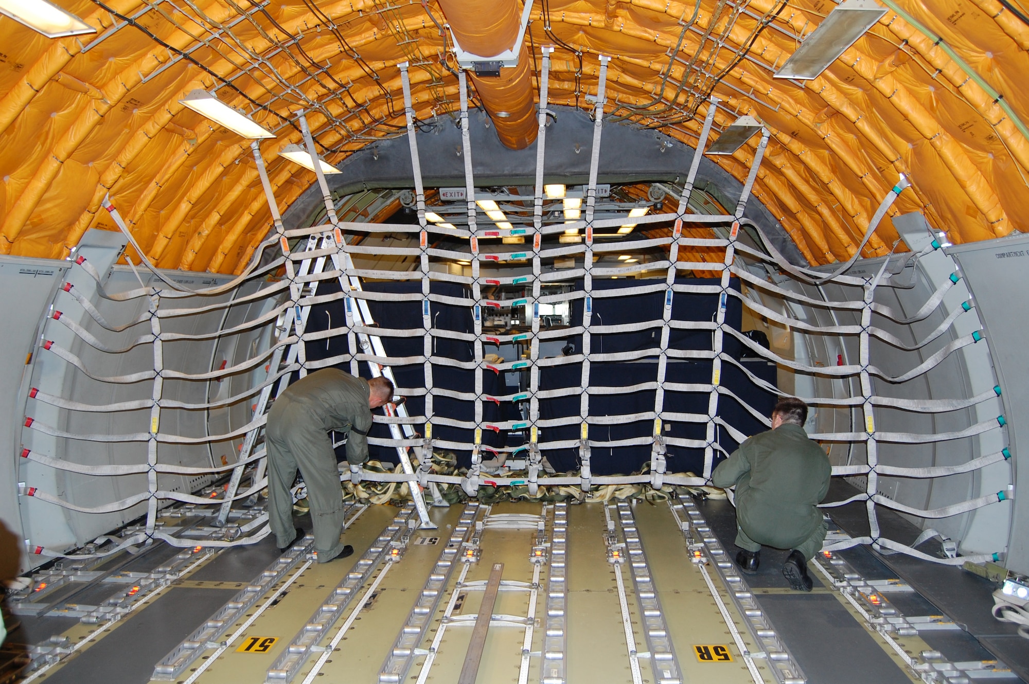Boom operators from McGuire Air Force Base, N.J., install an alternative, lightweight cargo net inside a KC-10 Extender Sept. 16 as part of a demonstration for the Air Mobility Battlelab.  The demonstration was for the Battlelab's KC-10 Lightweight Cargo Net and Hoist Initiative which was recommended for use to Air Mobility Command.  It was one of the last initiatives of the AMB, which deactivated Sept. 24 at the U.S. Air Force Expeditionary Center on Fort Dix, N.J.  (U.S. Air Force Photo/Tech. Sgt. Scott T. Sturkol)