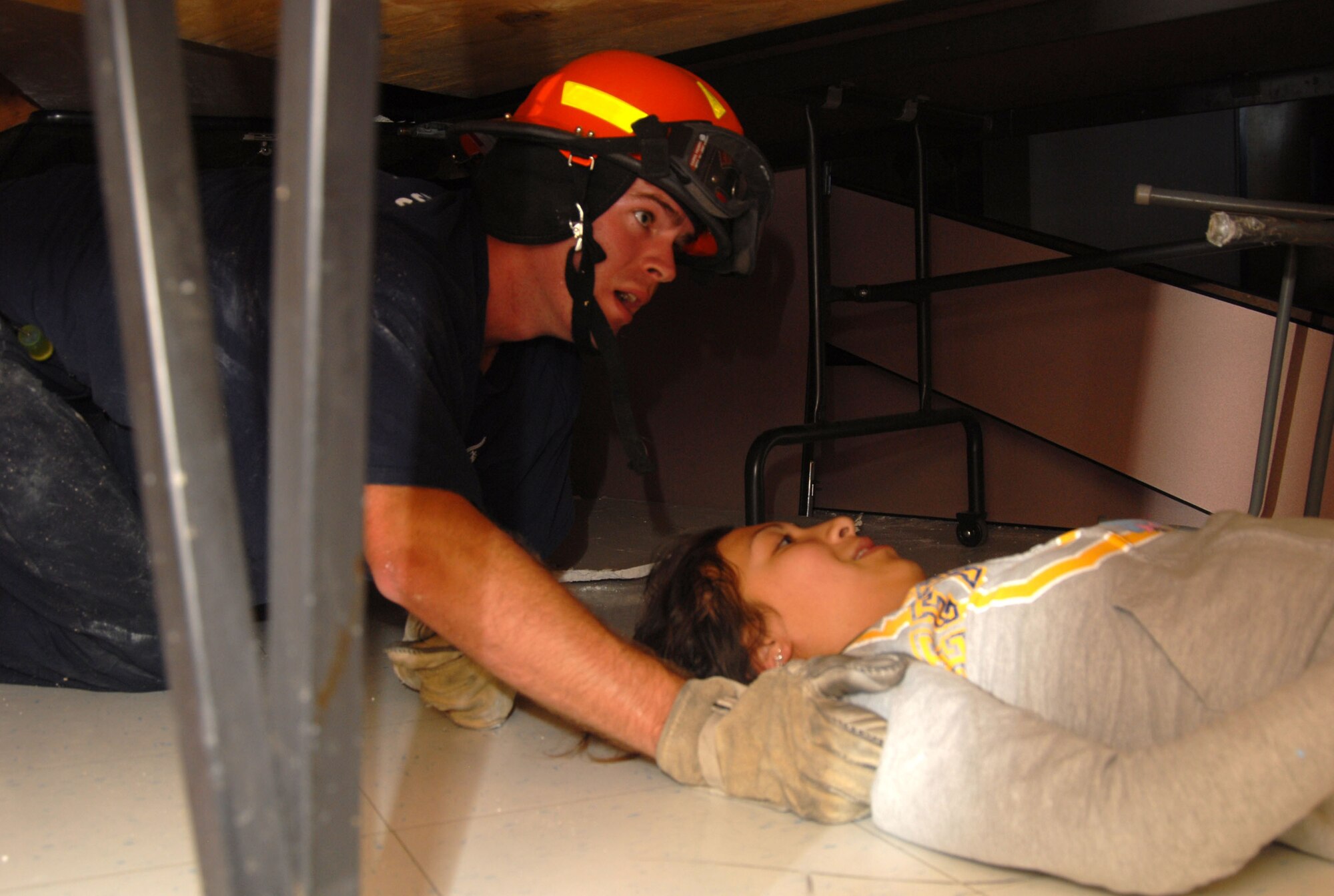 An Edwards firefighter evacuates a victim from school building rubble caused by a simulated magnitude 7.8 earthquake as part of the Great Southern California Shakeout earthquake drill. The exercise aims to help the base be prepared for a major earthquake. (Air Force photo by Senior Airman Julius Delos Reyes)