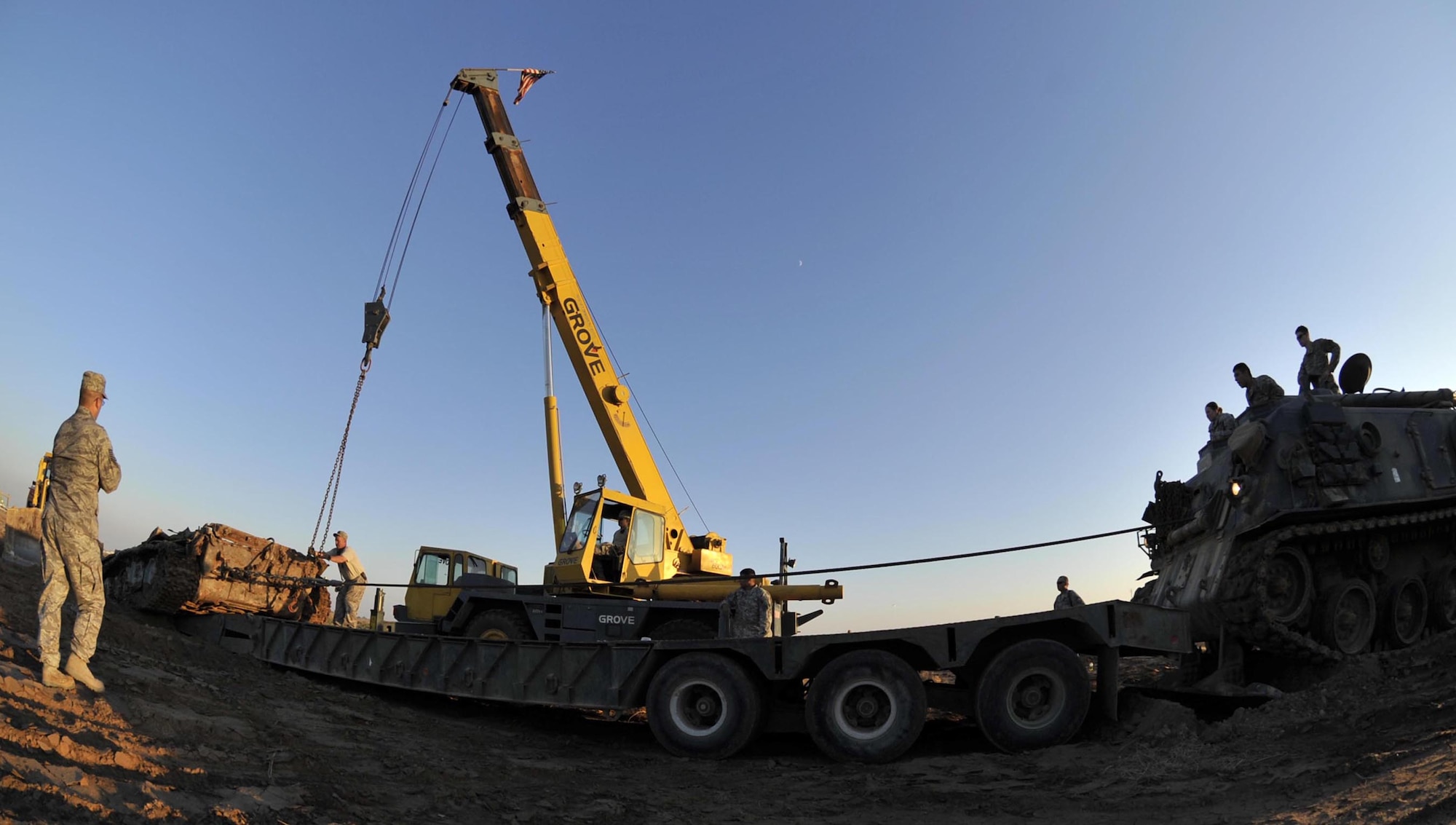 Airmen from the 447th Expeditionary Civil Engineer Squadron and Soldiers from the 503rd Maintenance Company work together with an M-88 tank recovery vehicle, a bulldozer and a crane to lift, pull and push an Iraqi T-72 Main Battle Tank from its grave and onto a trailer on the airfield at Sather Air Base, Iraq. The tank was an obstruction to safe airfield operations and had to be removed. (U.S. Air Force photo/Master Sgt. Brian Davidson)