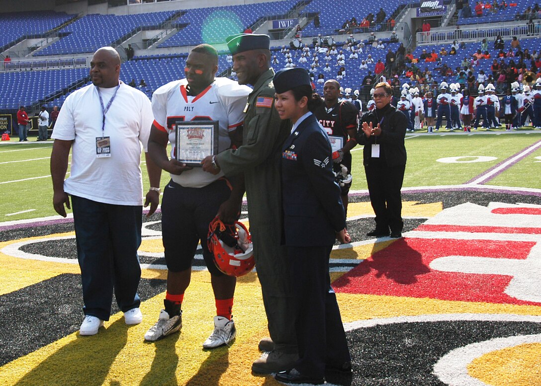 Brig. Gen. Alfred J. Stewart presents Arnold Farmer of Baltimore Polytechnic Institute High School a $500 college scholarship before game time Nov. 8 at M&T Bank Stadium in Baltimore. A Class of 1977 Baltimore Polytechnic Institute High School alumni, General Stewart shared inspirational words with both teams before the game and he presented a $500 college scholarship to a member of both high schools. General Stewart is the Air Force Recruiting Service commander. (U.S. Air Force photo/Tech. Sgt. Jennifer Lindsey) 