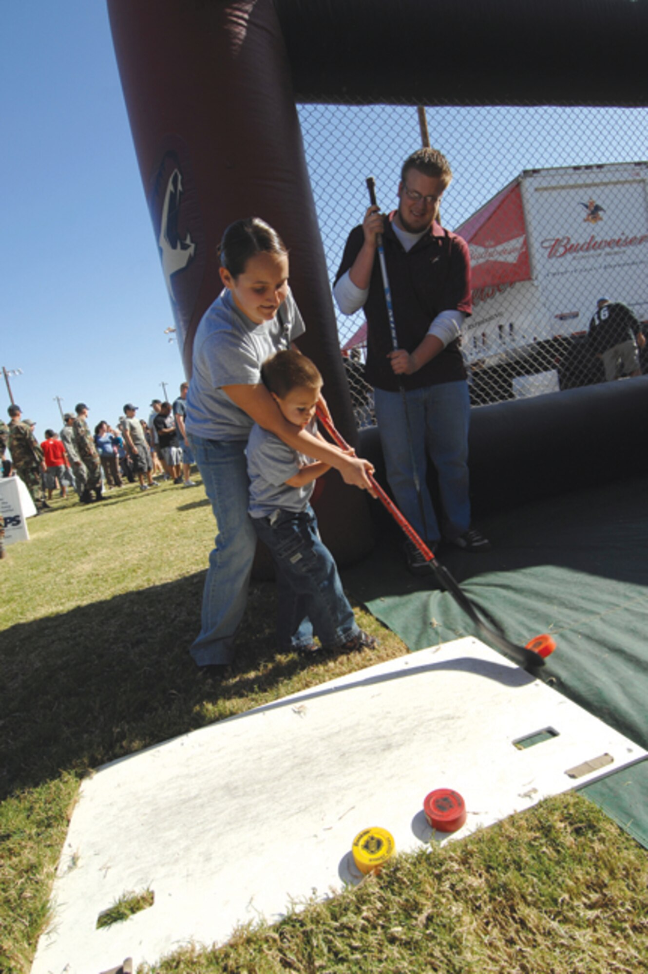 Airman 1st Class Amanda Esparza, 56th Equipment Maintenance Squadron, and here step-son, Alex Gonzalez, 4, team up for a slapshot challenge at the Phoenix Coyotes booth at the base Wingman Day picnic. (U.S. Air Force photo/ Tech. Sgt. Jeffery Wolfe.)