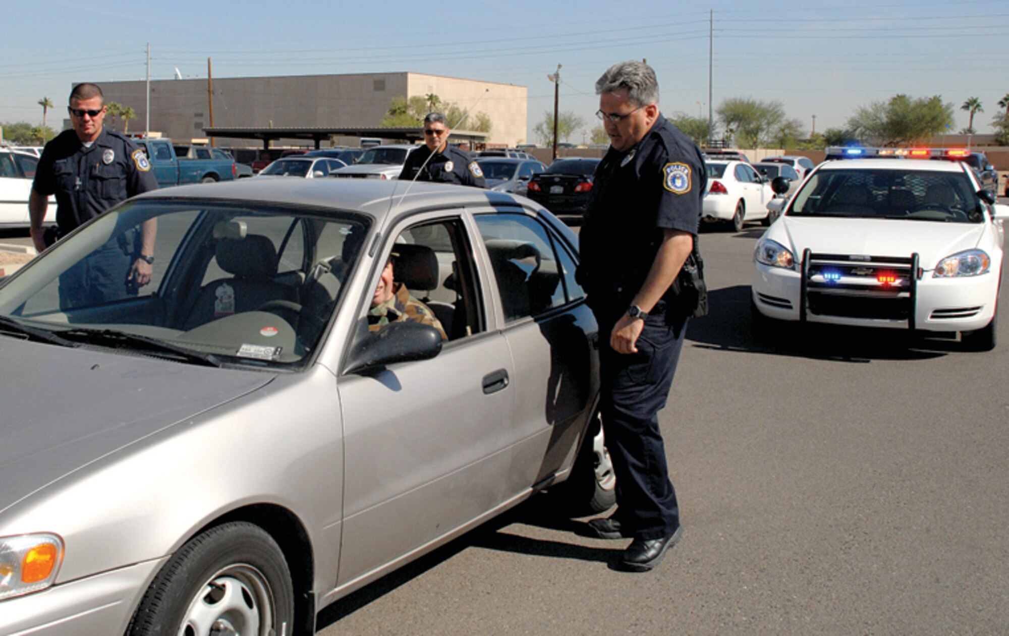 FROM LEFT: Officers Toby Boland, Rolando Gonzalez and Brian McManus, 56th Security Forces Squadron, perform a traffic stop in a parking lot on base during an exercise Oct. 24. Civilian officers participate in regular exercises to prepare them for real-world situations. (U.S. Air Force photo/ Airman 1st Class Tracie Forte.)