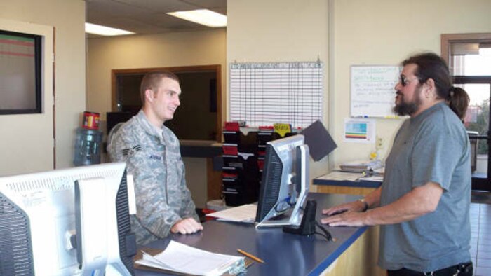Senior Airman Kyle Atkinson, air transportation journeyman with 99th Logistics Readiness Squadron, greets George Schultz, an Air Force retiree at the customer service desk of Nellis air terminal Nov. 5. (Air Force photo by Airman 1st Class Jonathan Cantrell)