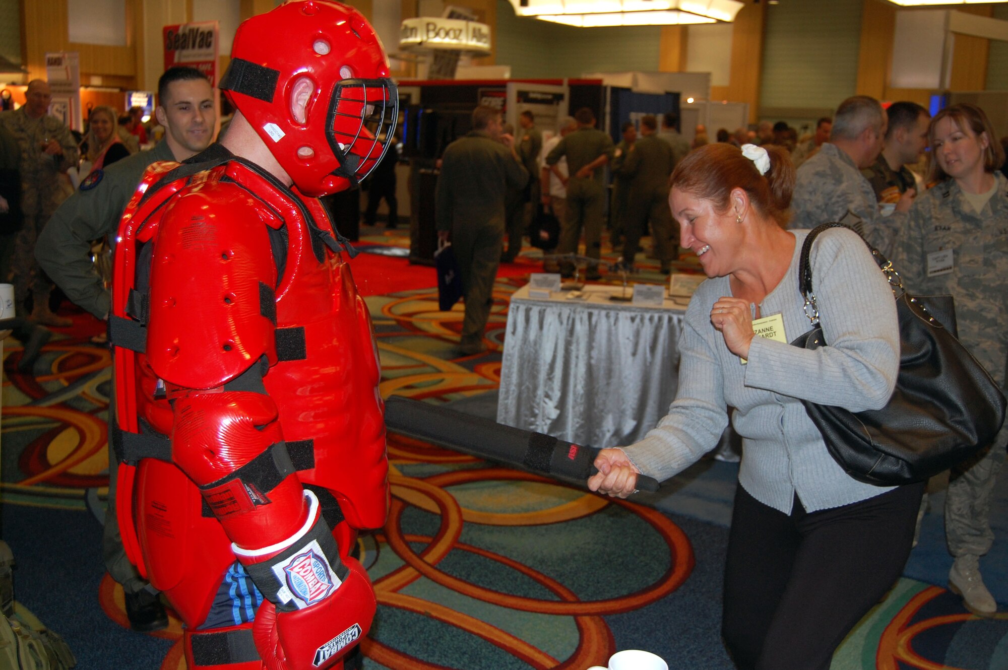 Suzanne Eckhardt, an attendee to the 2008 Airlift/Tanker Association convention in Anaheim, Calif., hits Master Sgt. Scott Pepper (in "red man" suit) with a padded baton Nov. 7 in the exhibit hall for the convention in Anaheim, Calif.  Sergeant Pepper, from the U.S. Air Force Expeditionary Center's 421st Combat Training Squadron at Fort Dix, N.J., was one of the Expeditionary Center's Airmen performing Phoenix Raven demonstrations in the exhibit hall. Throughout the convention, Sergeant Pepper and other members of the USAF EC were on hand to not only perform the demonstrations for the thousands of convention attendees, but also to support the center's booth that showed the Expeditionary Center mission.  (U.S. Air Force Photo/Tech. Sgt. Scott T. Sturkol)