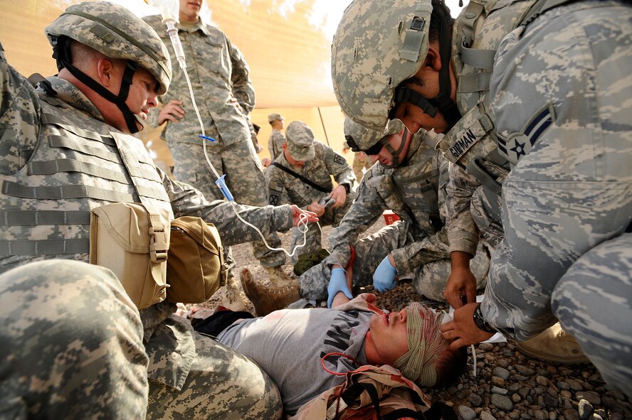 Airman 1st Class Jonathan Guzman (right) attaches tape to Army Spc. Jeremy Gary's head to indicate the time and date he received a tourniquet during a combat lifesaver course on Joint Base Balad, Iraq, Nov. 12. The Army, Air Force and Navy conducted a mass casualty exercise as the final training scenario of a joint CLS course. Airman Guzman, a security forces apprentice with the 532nd Expeditionary Security Forces Squadron, is deployed from Lackland Air Force Base, Texas. Gary, a joint node network operator maintainer, is assigned to the 51st Expeditionary Signal Battalion, deployed from Fort Lewis, Wash. (U.S. Air Force photo/Airman 1st Class Jason Epley) 