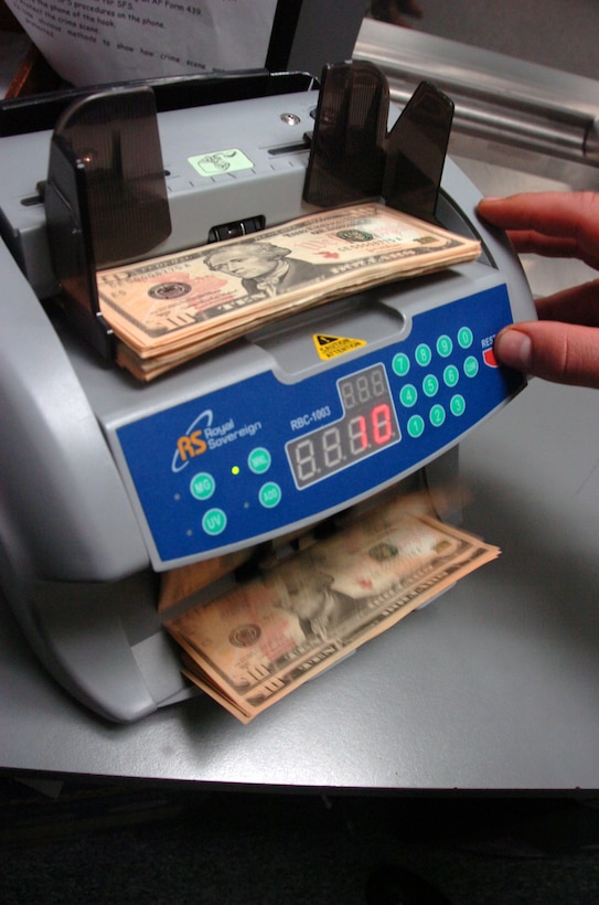 A 316th Comptroller Squadron financial service technician uses a money counter to count a large sum of money. The 316th Comptroller Squadron services approximately 26,000 customers in all matters of travel, military pay, civilian pay and all budgetary activities for the wing commander. (U.S. Air Force photo by Bobby Jones)