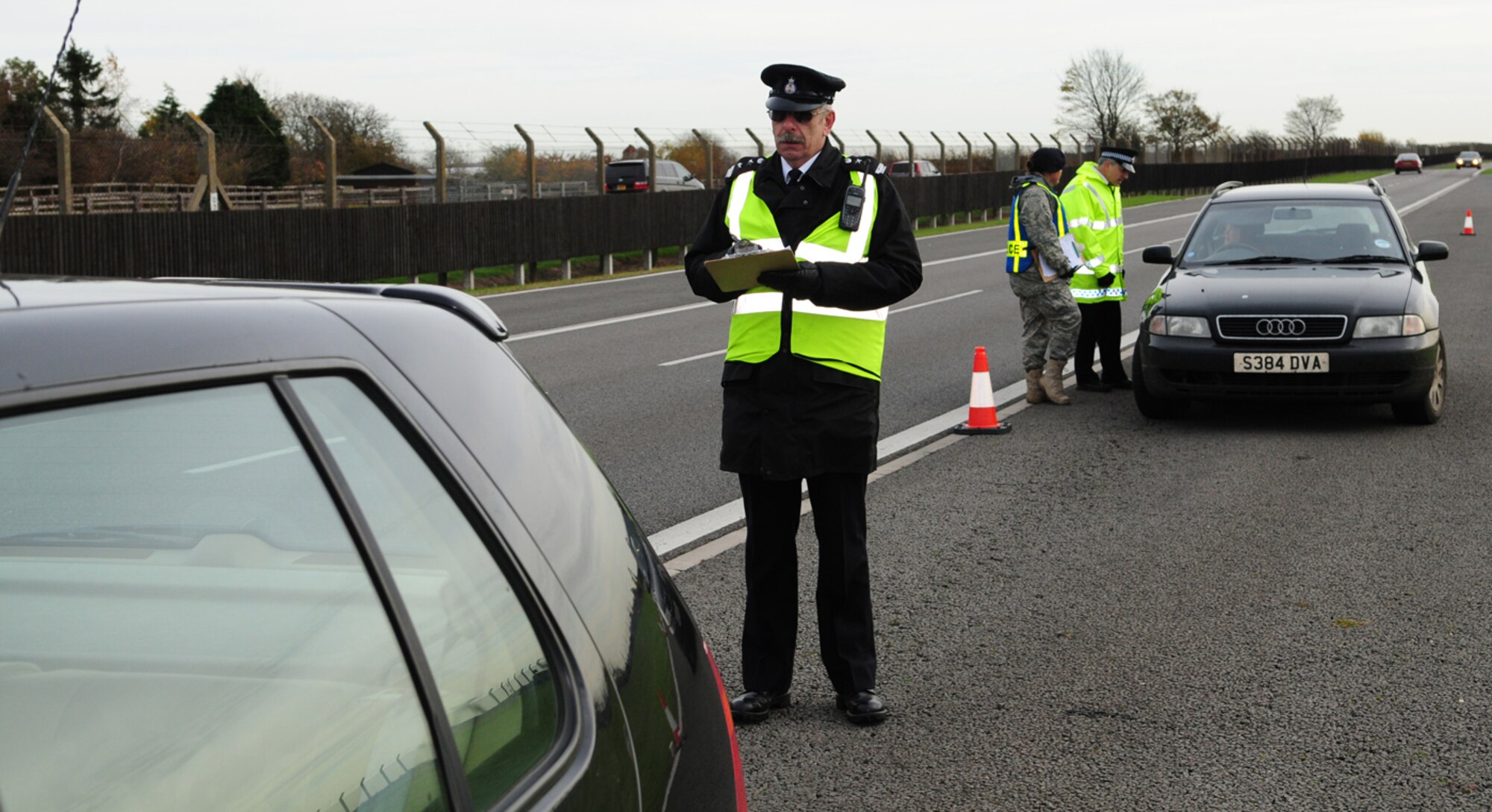 Civilian Security Officer 4 Ian Moore, MoD Police and Guarding Agency, checks the rear lights on a car during a winter driving safety campaign Nov. 13 at RAF Mildenhall. A total of 75 vehicles were randomly stopped and given winter safety checks by members of the MoD Police, MoD Police and Guarding Agency, 100th Security Forces Squadron and 100th ARW Safety personnel, who worked together to ensure safe vehicles. They checked tires, lights and windshields, and provided advice on equipment to keep in the car. Suggested cold weather driving equipment included an ice scraper, flashlight, jumper cables, warm clothing and a blanket. They also recommended keeping items such as a warning triangle, first aid kit, high visibility vest and mobile phone permanently in vehicles. (U.S. Air Force photo by Karen Abeyasekere)