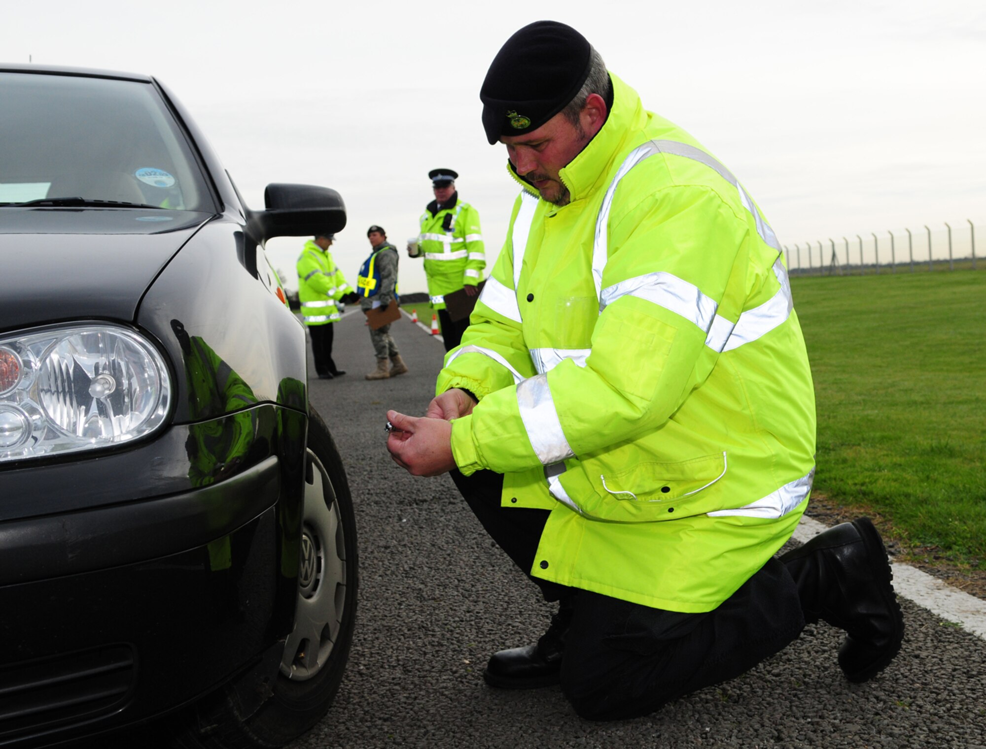 Civilian Security Officer 5 Mark Osbourne, Ministry of Defence Police and Guarding Agency, checks the tire pressure on a vehicle pulled over for winter safety checks as part of the winter driving safety campaign. MoD Police, MoD Police and Guarding Agency, 100th Security Forces Squadron and 100th ARW Safety personnel worked together performing winter safety checks on vehicles. They checked tires, lights and windshields, and provided advice on equipment to keep in the car. Suggested cold weather driving equipment included an ice scraper, flashlight, jumper cables, warm clothing and a blanket. They also recommended keeping items such as a warning triangle, first aid kit, high visibility vest and mobile phone permanently in vehicles. Seventy-five vehicles were checked at RAF Mildenhall. (U.S. Air Force photo by Karen Abeyasekere)