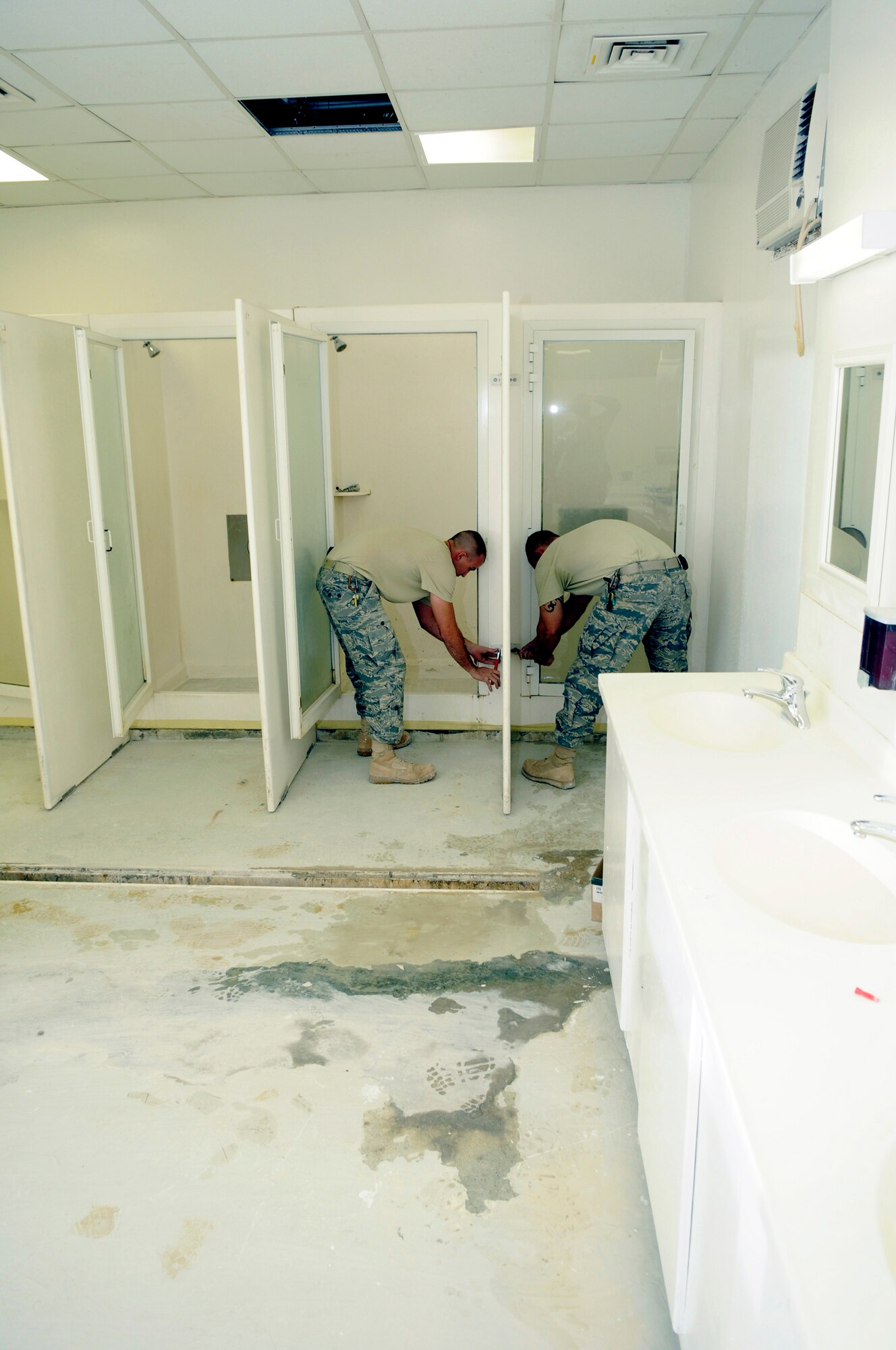 Senior Airman Nathan Straub and Staff Sergeant Nic Bevilacqua, structural journeymen assigned to the 379th Expeditionary Civil Engineer Squadron, tighten bolts on the lower portion of a shower divider, Nov. 13, at an undisclosed air base in Southwest Asia.  The cleaned up shower areas are one of the sections that are updated in a temporary restroom facility during refurbishment.  The refurbished units will cover the time frame until permanent restrooms are ready for use.  Sergeant Bevilacqua hails from Victorville, Calif., and is deployed from Fairchild Air Force Base, Wash.  Airman Straub is a native of Taunt, Mass., and deployed from Grand Forks AFB, N.D.  Both are here in support of Operations Iraqi and Enduring Freedom and Joint Task Force-Horn of Africa.  (U.S. Air Force photo by Tech. Sgt. Michael Boquette/Released)