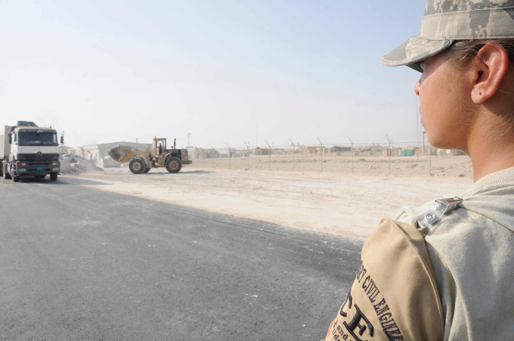 Senior Airman Brenna Reynolds, escort assigned to the 379th Expeditionary Civil Engineer Squadron, watches the third country national contractors as they work  Nov. 13, at an undisclosed air base in Southwest Asia. The 379 ECES escort members stay vigilant to ensure third country national contractors here complete their jobs and don?t perform any acts that would endanger deployed members. Airman Reynolds, a native of Van Horn, Texas, is deployed from Shaw Air Force Base, S.C., in support of Operations Iraqi and Enduring Freedom and Joint Task Force-Horn of Africa. (U.S. Air Force photo by Staff Sgt. Darnell T. Cannady/Released)