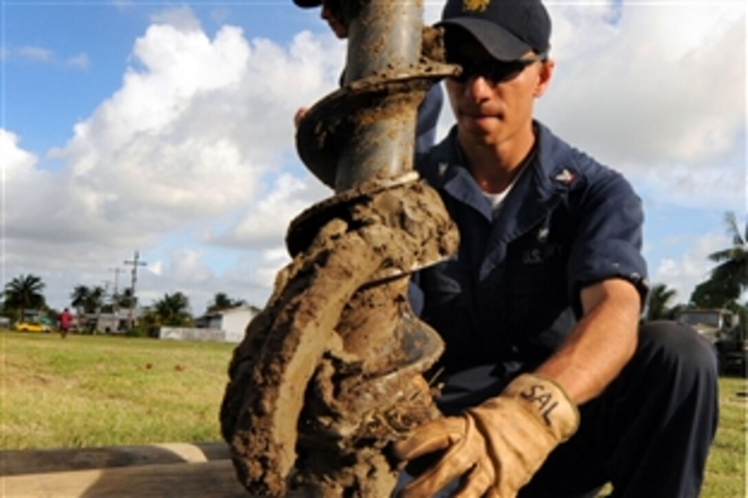 U.S. Navy Petty Officer 3rd Class William Anderson embarked aboard the amphibious assault ship USS Kearsarge, Georgetown, Guyana, Nov. 12, 2008, cleans mud from a drill bit used to drill holes for new light poles at East Ruimveldt Community Center during the humanitarian and civic assistance mission Continuing Promise 2008.