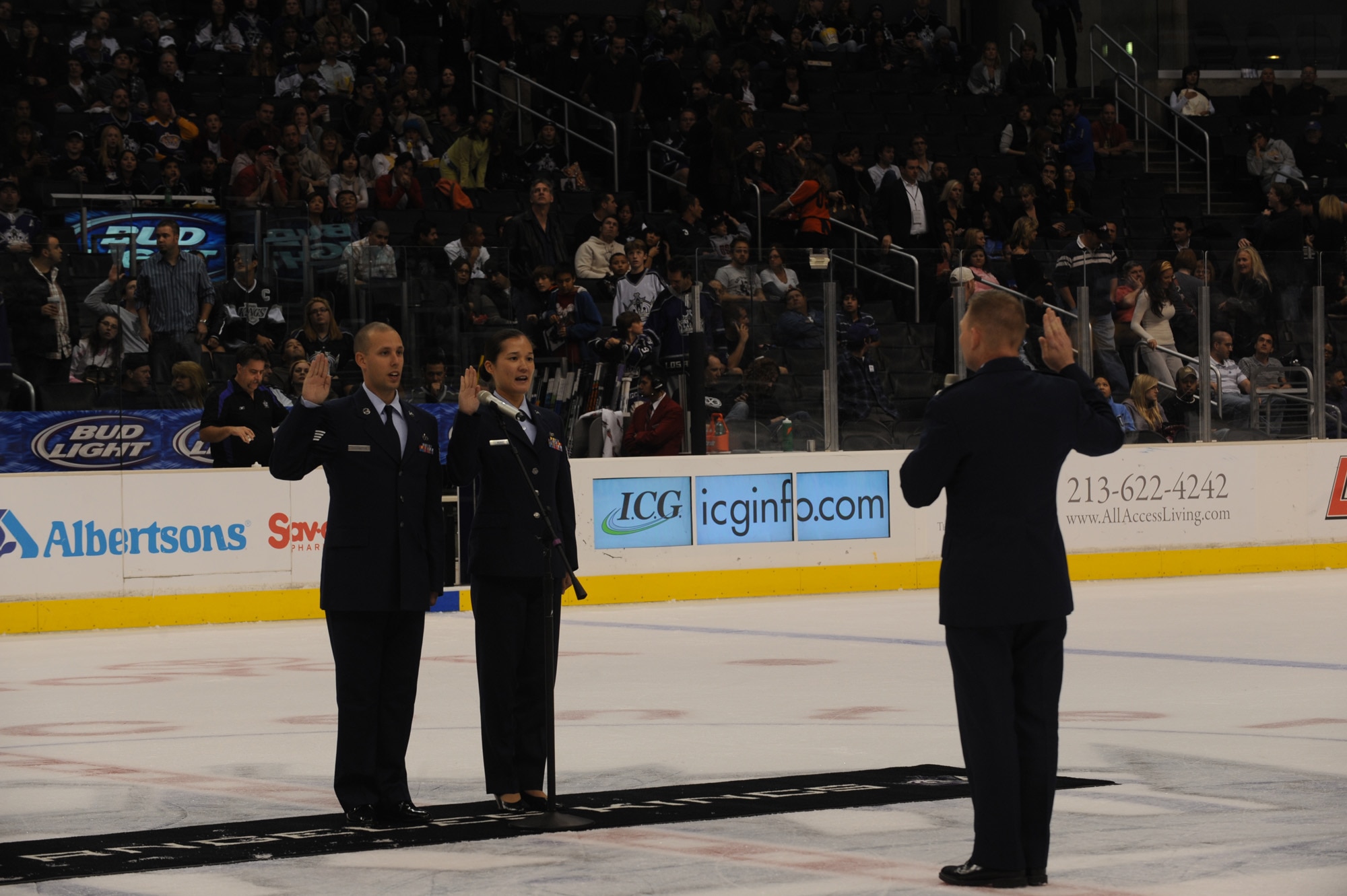 Col. John Odey swears in Tech. Sgt. Surita Rorie and Staff Sgt. Robert Coddington on the ice of the Staples Center, Los Angeles, Calif., Nov. 15. Sergeants Rorie and Coddington reenlisted during a Los Angeles Kings vs. Nashville Predator game as part of Air Force Week Los Angeles. Colonel Odey is the 95th Communications Group Commander, Edwards Air Force Base, Calif. Sergeants Rorie and Coddington are stationed at Edwards Air Force Base, Calif. Air Force Week Los Angeles is an event designed to educate the local population about the Air Force's capabilities and missions through various activities and exhibitions all over the Los Angeles area. It provides an up close and personal look at the men and women of the Air Force serving worldwide in the defense of freedom. Air Force Week Los Angeles runs from Nov. 14 to 21.  (U.S. Air Force photo/Staff Sgt. Desiree N. Palacios)