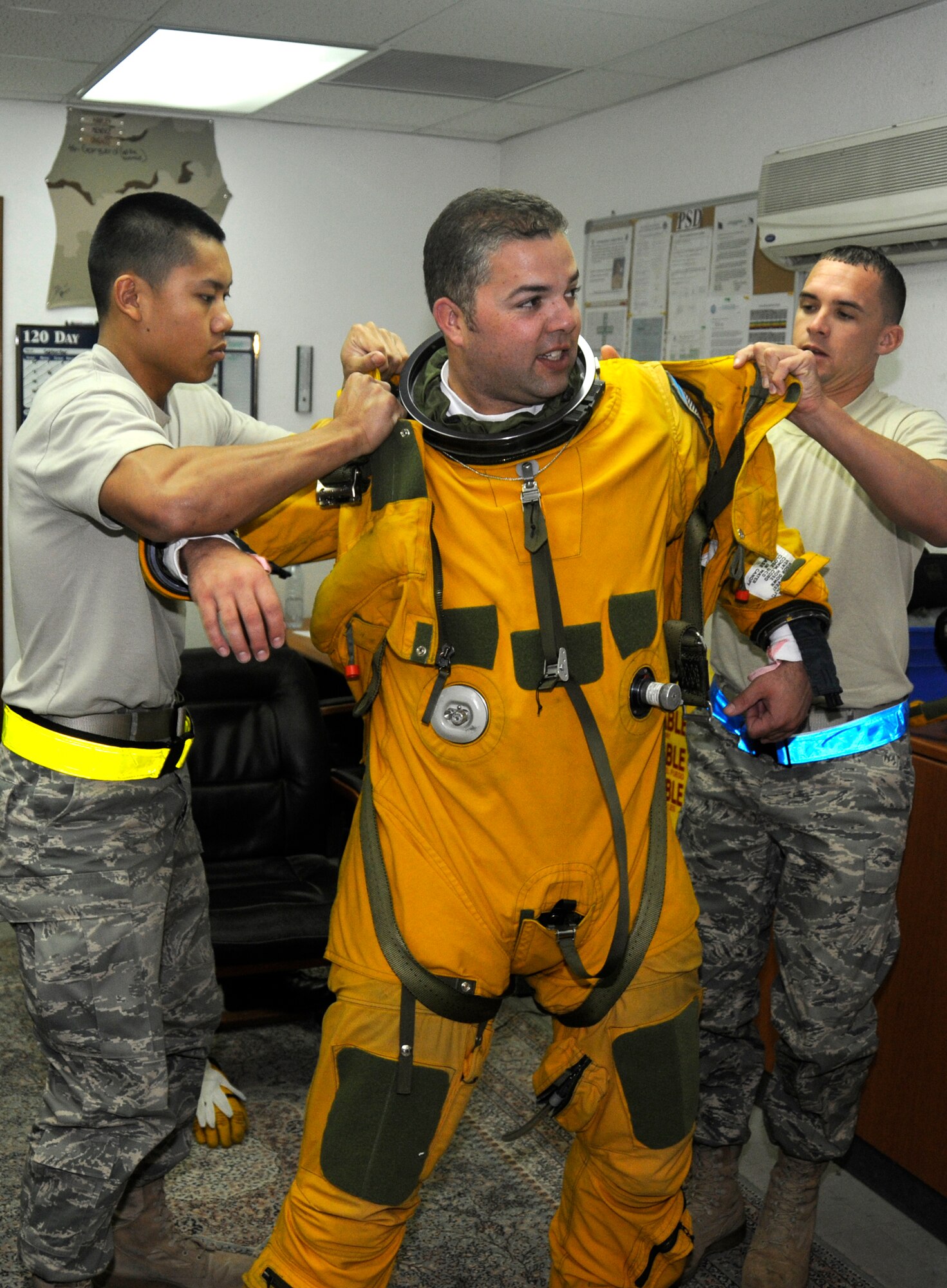 SOUTHWEST ASIA -- Lt. Col. Brian "Bubba" Dickinson gets help from Senior Airman David Sivixay(left) and Senior Airman Allen Smith putting on a full pressure suit here Nov. 14. Both are with the 99th Expeditionary Reconnaissance Squadron Physiological Support Division. Col. Dickinson is a U-2 Dragonlady pilot with the 99th ERS and is responsible for gathering intelligence in the area of responsibility in support of Operation Iraqi and Enduring Freedom. All three are deployed from the 9th Reconnaissance Wing out of Beale Air Force Base, Calif. Airman Sivixay is from San Diego, Calif. Airman Smith's hometown is Tampa, Fla. and Colonel Dickinson is a native of Oscoda, Mich., and Colorado Springs, Colo.(U.S. Air Force photo/Tech. Sgt. Christopher A. Campbell)(released)