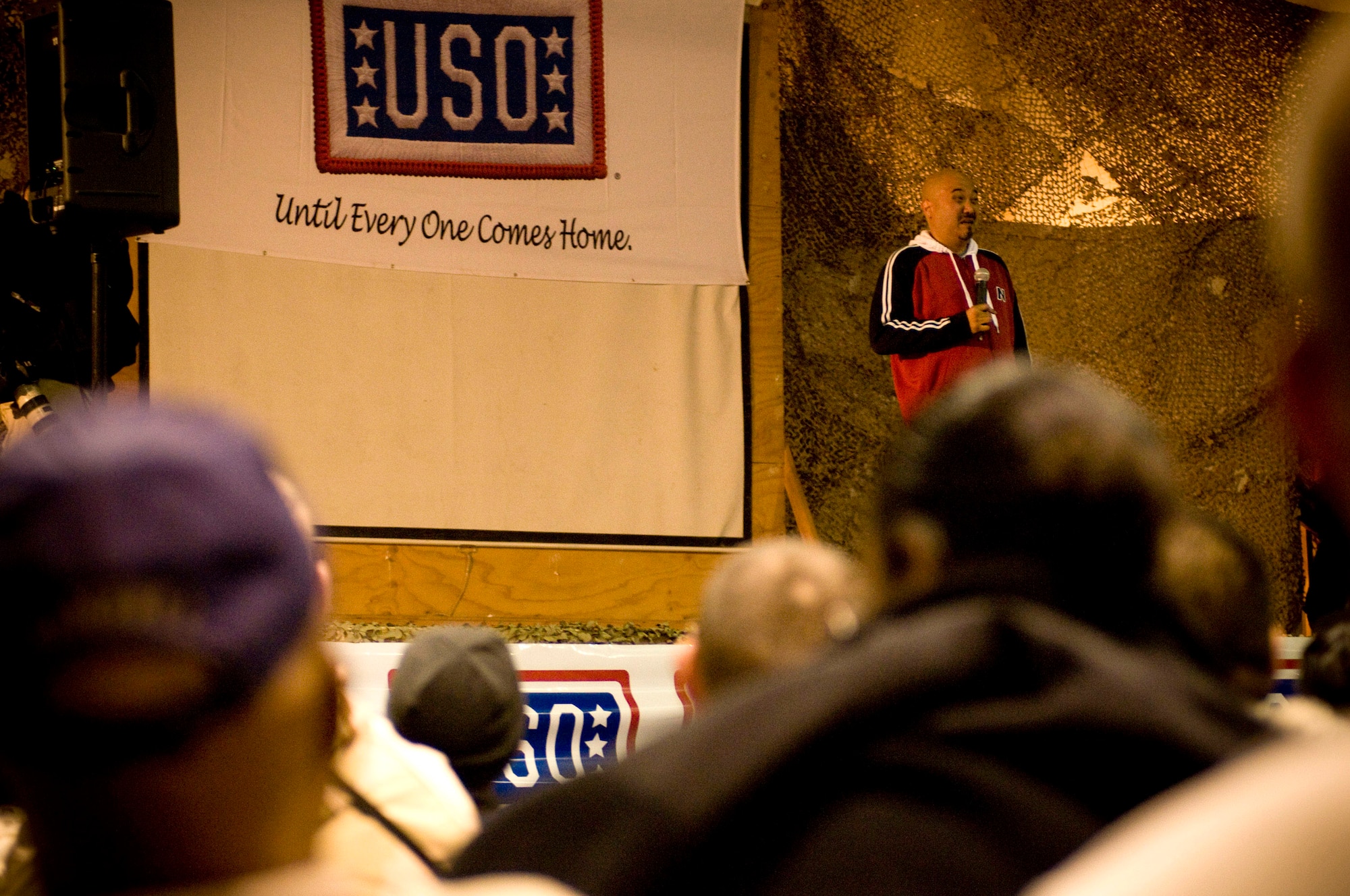 Edwin San Juan tells a joke to a crowd of Airmen and Soldiers Nov. 13 at Bagram Airfield, Afghanistan. Mr. San Juan is a comedian and emcee for the USO Tour entitled "Around the World in 8 Days." (U.S. Air Force photo/Staff Sgt. Samuel Morse)