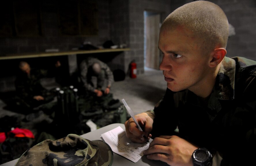 MOODY AIR FORCE BASE, Ga. -- An Airman writes down important information in preparation for an upcoming training scenerio, while other Airmen tie down night vision equipment during training here Nov. 14. Airmen from Moody must complete this prerequisite before they are even considered as candidates for the 9-week U.S. Army Ranger training course. (U.S. Air Force photo by Senior Airman Gina Chiaverotti)