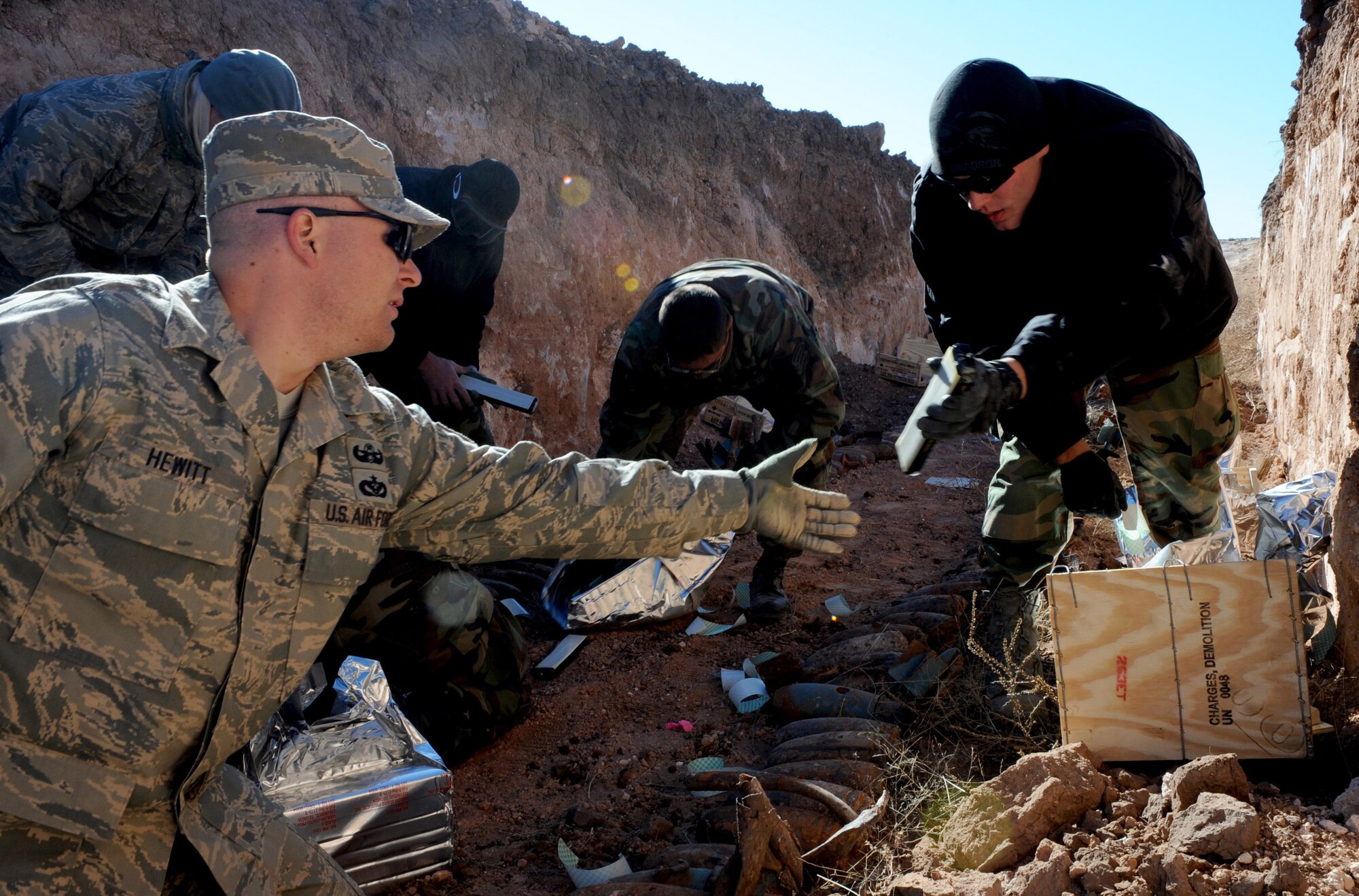 CANNON AIR FORCE BASE, N.M. -- Staff Sgt. David Hewitt, 27th Special Operations Civil Engineer Squadron's Explosive Ordnance Flight, hands C-4 explosive to Airman 1st Class Nathan Baloga, also with EOD, Nov. 6.  The Airmen were planting demolition charges at Melrose Air Force Range as part of their annual range clearance. (U.S. Air Force photo/Airman 1st Class Evelyn Chavez)