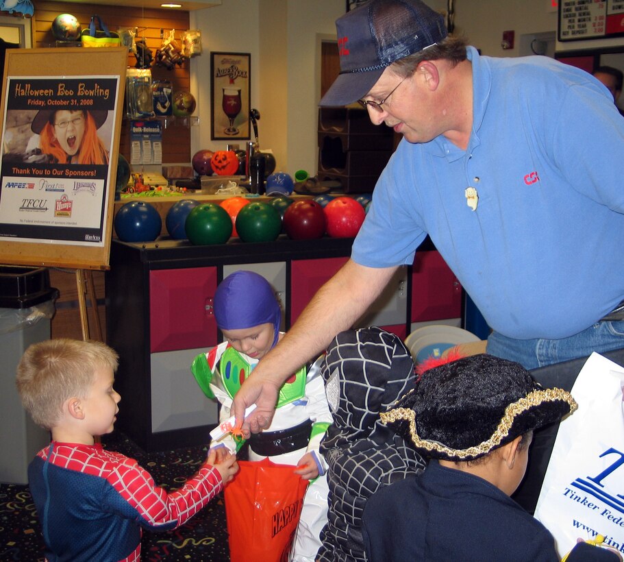 Ken Broder, Vance Bowling Center manager, hands out Halloween goodies to children from the Child Development Center on Friday, Oct. 31, during Boo-bowling activities. The children, part of the Pumpkin Parade, sang Halloween songs and went trick-or-treating around base. (Contributed photo by Melissa Seror)