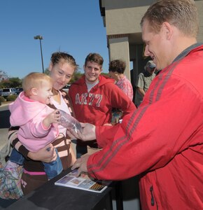 Second Lt. John Brandes (from left), his wife, Ericka, and their daughter, Aleigha, pick up free recycled products given away by the recycling center staff during the America Recycles initiative Nov. 15 at the base exchange. (U.S. Air Force photo by Melissa Peterson)