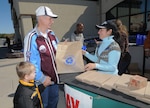 Retired Navy Chief Warrant Officer William Sneed and his grandson, Titus Wilson, pick up a free bag of recycled products Nov. 15 at the base exchange from Michelle Benavidez, Randolph Air Force Base Recycling Center, as part of the America Recycles initiative. (U.S. Air Force photo by Melissa Peterson)