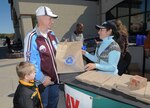 Retired Navy Chief Warrant Officer William Sneed and his grandson, Titus Wilson, pick up a free bag of recycled products Nov. 15 at the base exchange from Michelle Benavidez, Randolph Air Force Base Recycling Center, as part of the America Recycles initiative. (U.S. Air Force photo by Melissa Peterson)