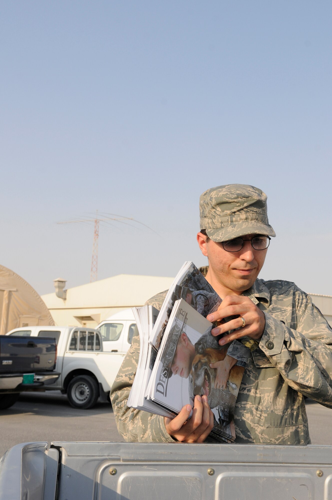 Senior Airman Clinton Atkins, journalist assigned to the 379th Air Expeditionary Wing, gathers freshly printed Desert Eagle news magazines for delivery to the Passenger Terminal, Nov. 16, at an undisclosed air base in Southwest Asia.  The Desert Eagle magazine keeps deployed members abreast of the latest happenings and is a primary communication tool for the 379 AEW commander.  Airman Atkins, a native of San Antonio, Texas, is deployed from Altus Air Force Base, Okla., in support of Operations Iraqi and Enduring Freedom and Joint Task Force-Horn of Africa. (U.S. Air Force photo by Tech. Sgt. Michael Boquette/Released)