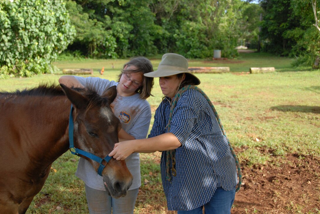 ANDERSEN AIR FORCE BASE, Guam - Deanna Tofte helps her daughter Shanna how a bridal a horse at the Horses of Sleepy Meadows Ranch in Yigo, Guam.  (U.S Air Force photo by Tech. Sgt. Brian Bahret)