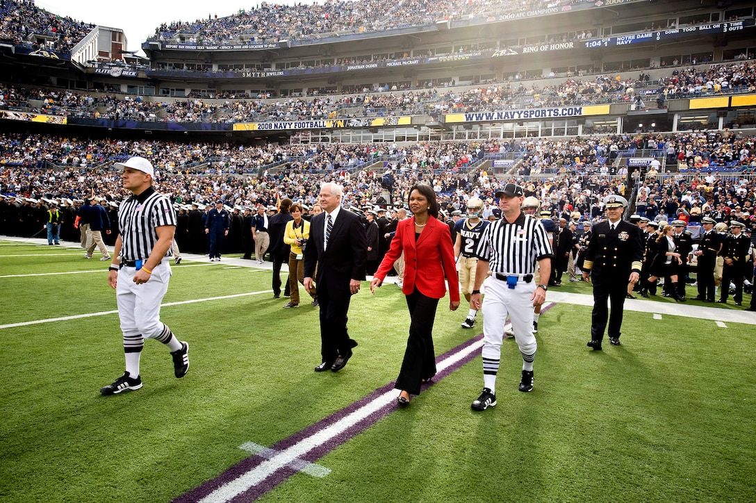 Secretary of State Condoleezza Rice and Defense Secretary Robert M. Gates walk out onto the field to participate in the coin toss prior to the start of the Navy vs. Notre Dame football game in Baltimore, Nov. 15, 2008.