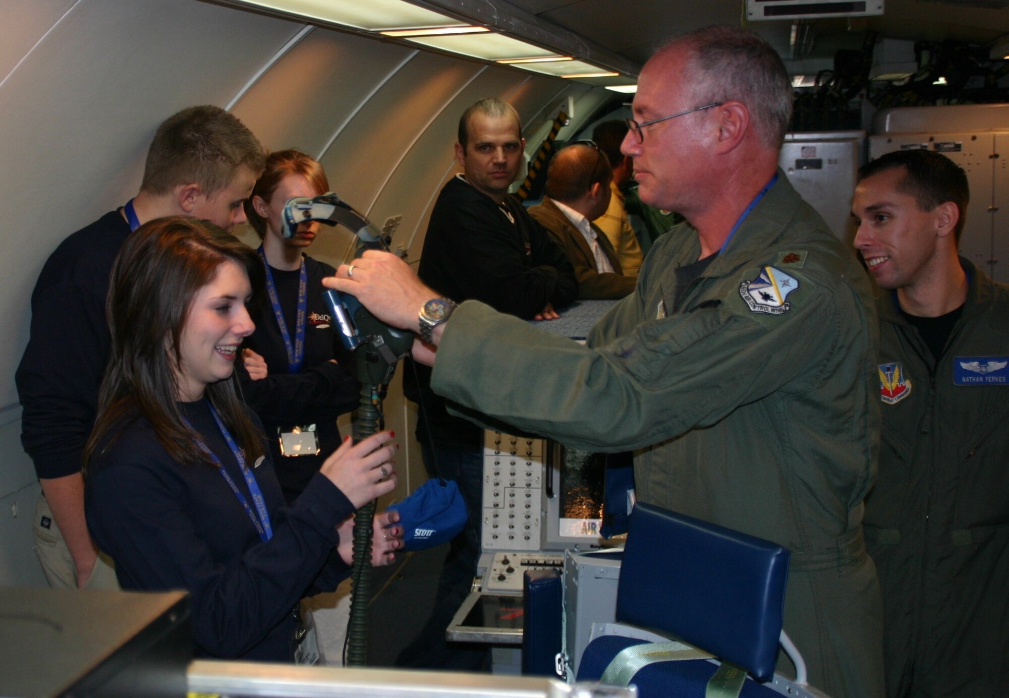 Maj. Rich Stikeleather, 966th Airborne Air Control Squadron, helps one of the DelQuest students try on an oxygen mask during her tour of the E-3 Sentry. Photo compliments of 1Lt Kinder Blacke.