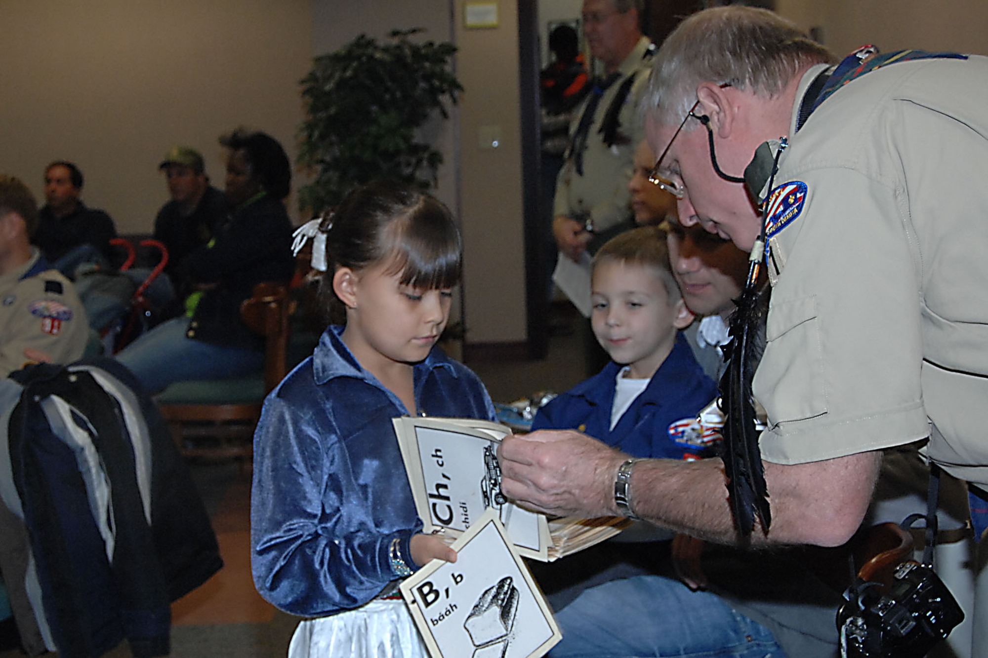 OFFUTT AIR FORCE BASE, Neb. -- Brianna Rehm takes a copy of the Navajo alphabet around the room for the audience to view up close during a presentation at a Native American story telling event at the library here Nov. 15. Ray Hefner, a member of the Eagle Eye Patrol and U.S. Strategic Command government civilian, looks closely through the book. This event helped the Boy Scouts fulfill the requirements for one of five badges or tickets for diversity.  (U.S. Air Force Photo By Kendra Williams)