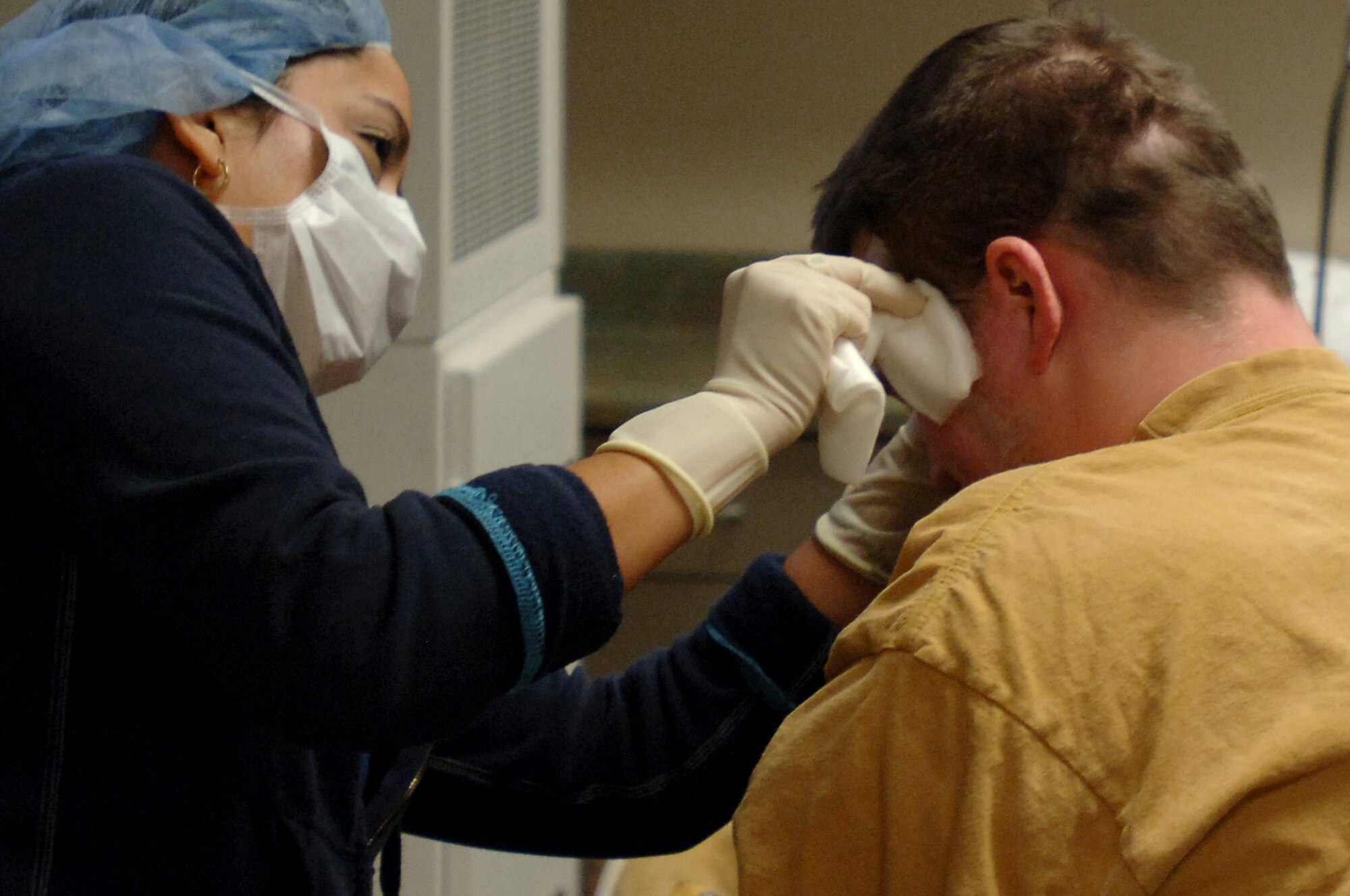 A technician at refractive surgery services removes bandages from Army Sergeant Robert Stephenson, 3rd Battalion, 509th Parachute Infantry Regiment, Nov. 12 at Lackland Air Force Base, Texas. Sergeant Stephenson's hands were injured by an explosion in Iraq and laser eye surgery will make his daily routine easier. (U.S. Air Force photo by Staff Sgt. Erin M. Peterson)